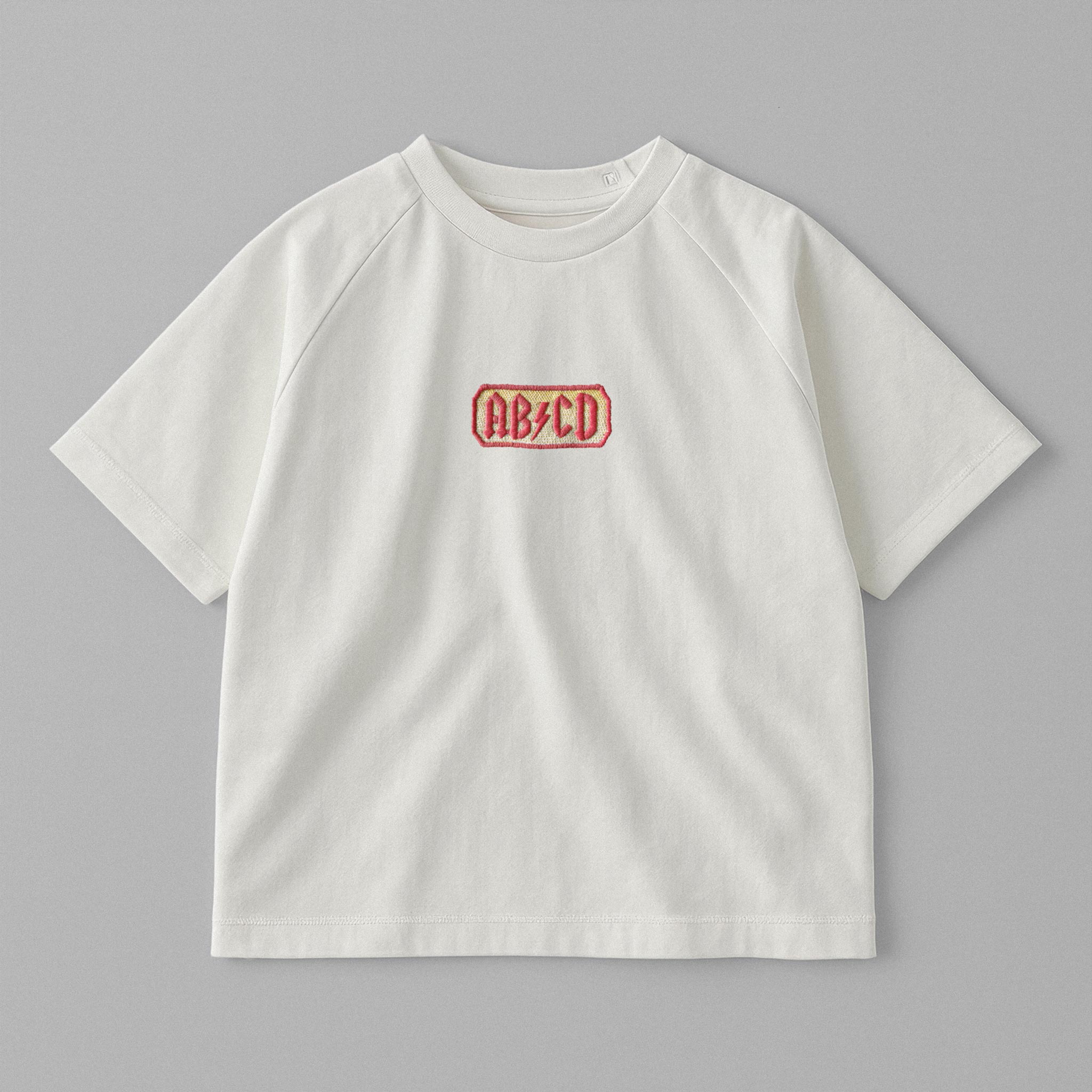 Ekru renkli, reglan kollu, omuzdan çıtçıtlı bebek tişörtü. Göğüs kısmında AC/DC logosu stilinde "AB/CD" nakışı bulunmaktadır.