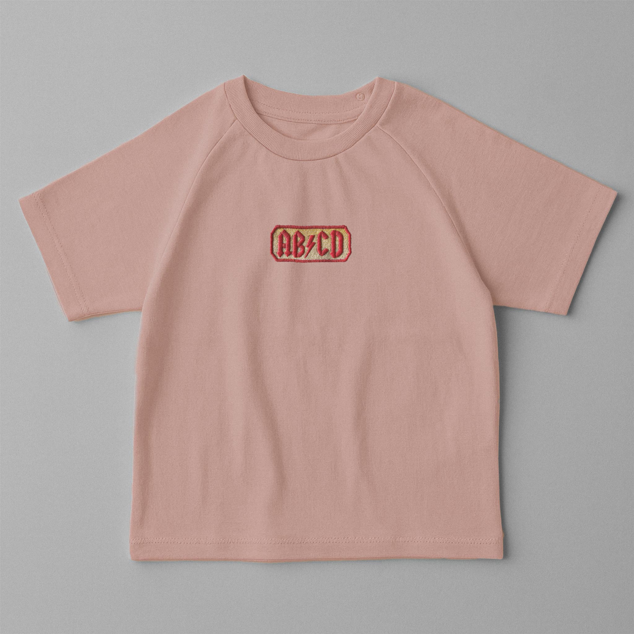 Gül kurusu (pembe) renkli, reglan kollu, omuzdan çıtçıtlı bebek tişörtü. Göğüs kısmında AC/DC logosu stilinde "AB/CD" nakışı bulunmaktadır.
