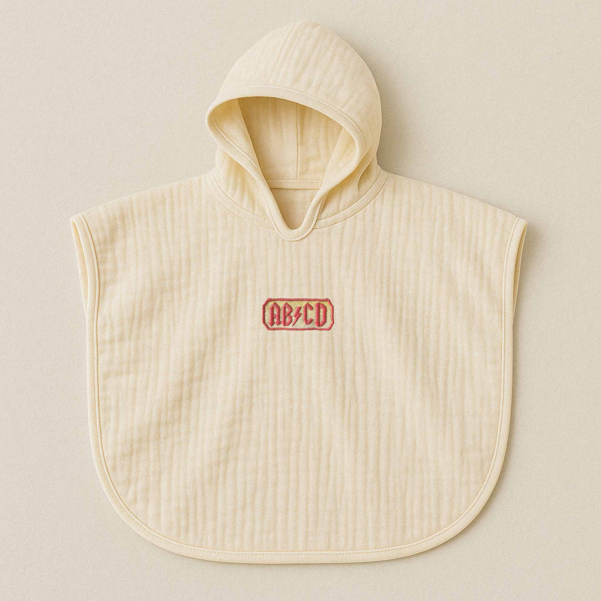 Ekru (doğal bej) renginde, kapüşonlu, müslin kumaştan bebek ve çocuk pançosu. Göğüs kısmında AC/DC logosu stilinde kırmızı "AB/CD" yazısı işlenmiştir.