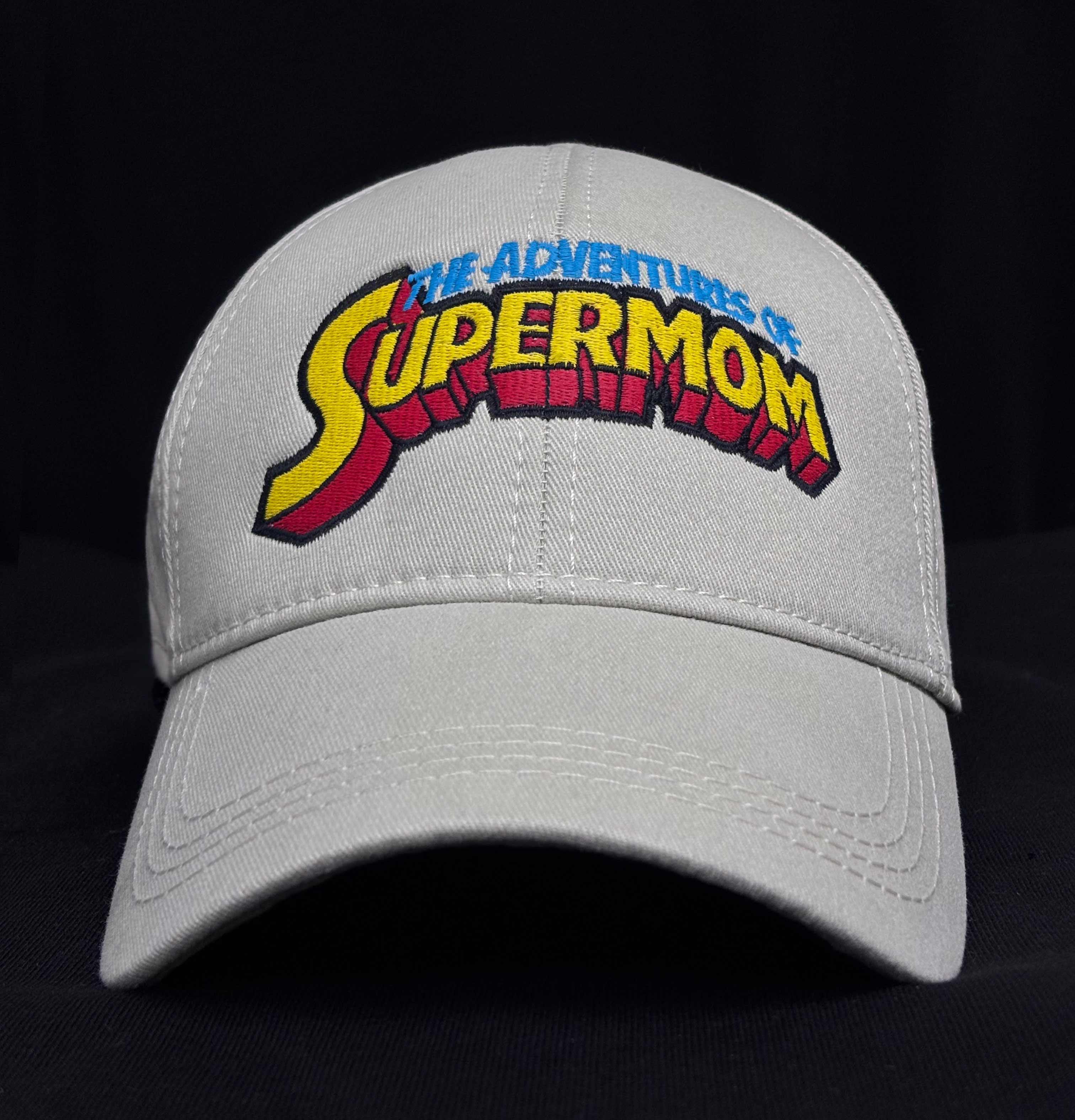 İç astarı ve dış yüzeyi %100 pamuktan üretilmiş açık gri renkli premium anne şapkası. Ön panelinde çizgi roman stili çok renkli "The Adventures of SUPERMOM" yazısı yüksek kalite Alman nakış işçiliğiyle işlenmiştir. Nefes alan yapısıyla terletmez ve gün boyu konfor sağlar. Annelerin günlük stiline dinamik bir dokunuş katan dayanıklı ve dikkat çekici bir aksesuardır.