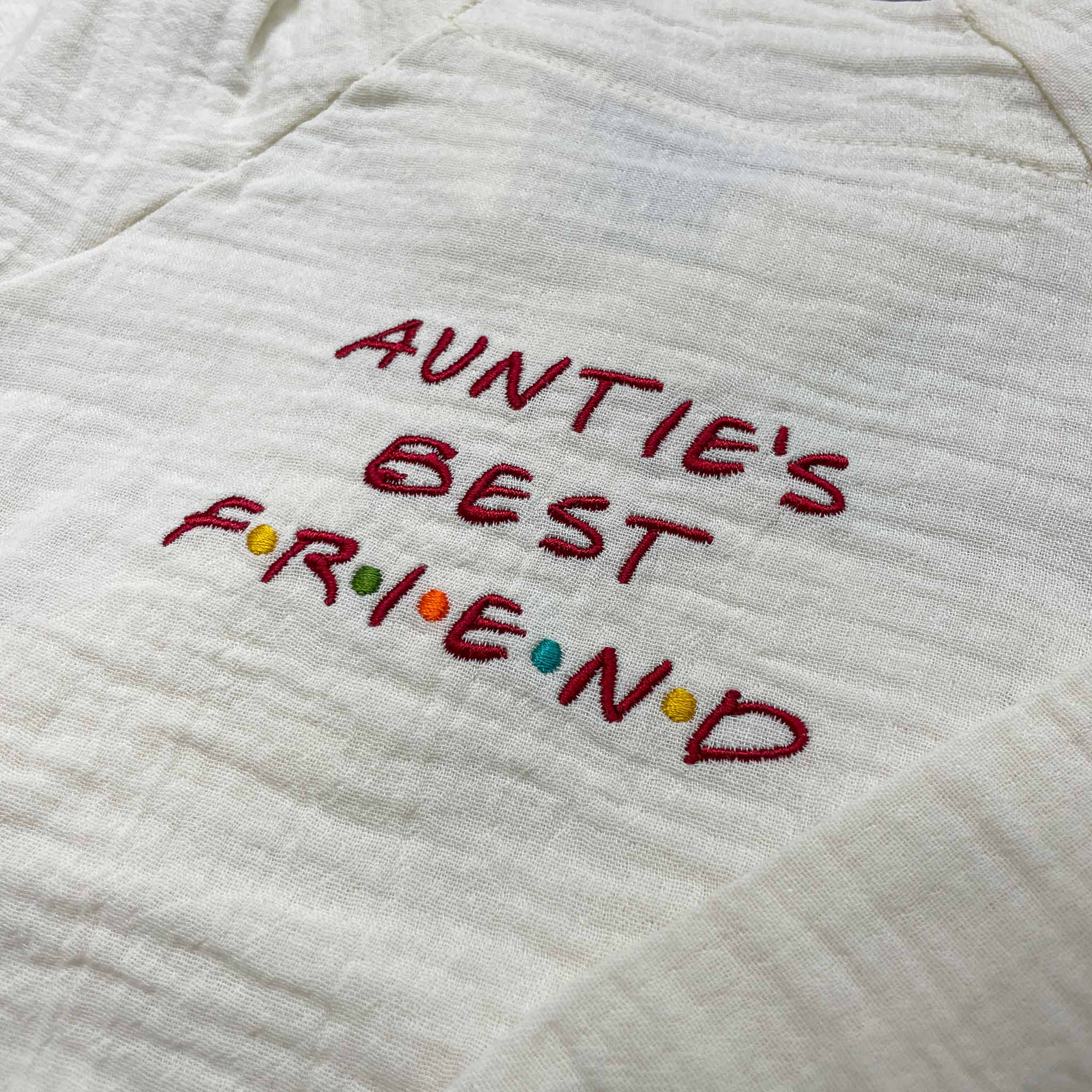 Doğal bej (ekru) renginde, %100 pamuklu müslin çocuk kimono takımı. Göğüs kısmında kırmızı iplik ve renkli noktalarla işlenmiş eğlenceli "AUNTIE'S BEST FRIEND" nakışı yer alır. Hassas ciltlere dost, nefes alan ve terletmeyen hafif dokusuyla öne çıkan, konforlu premium bebek ve çocuk takımı.