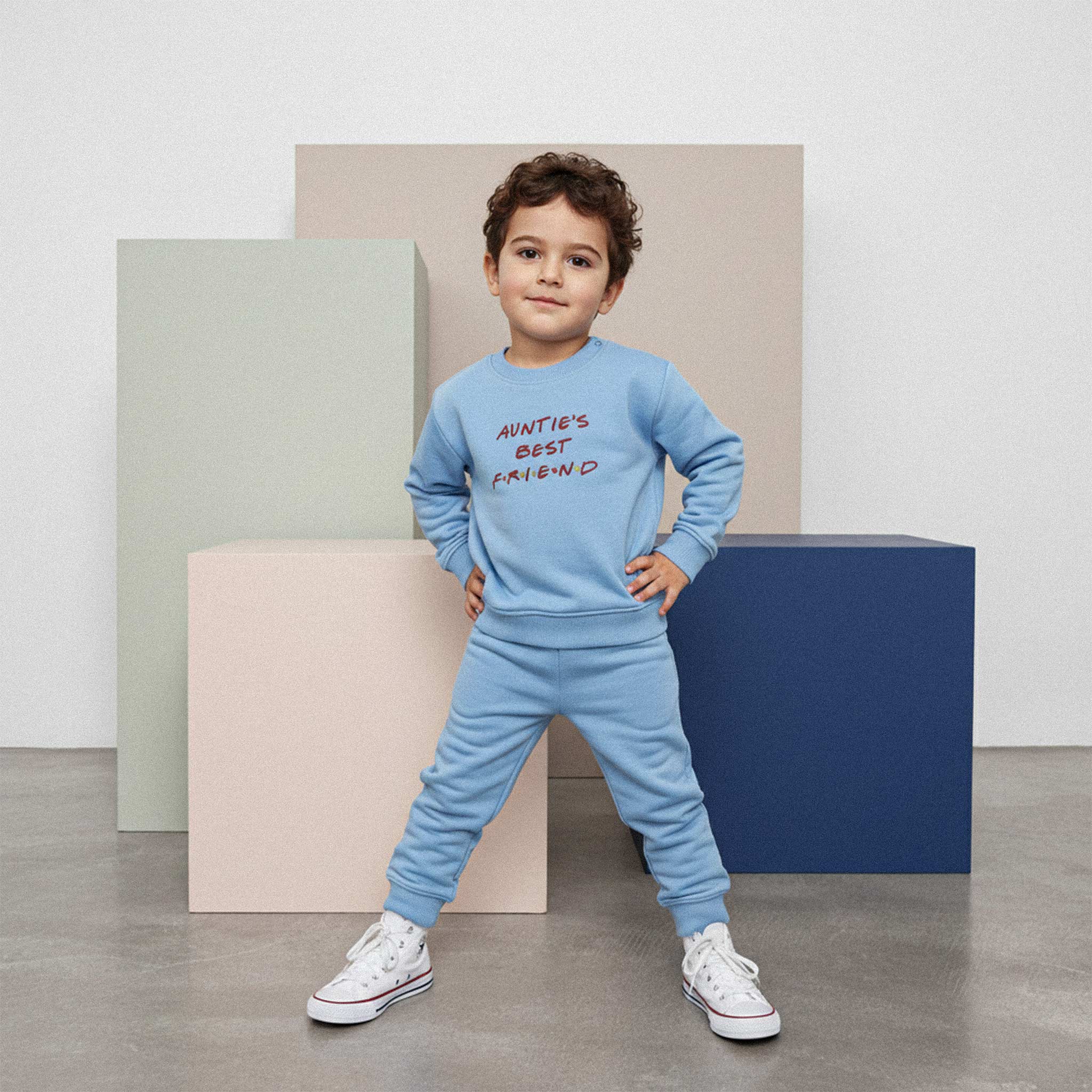 Mavi renkli 'Auntie's Best Friend' eşofman takımı giyen erkek çocuk, elleri belinde kendinden emin bir şekilde poz veriyor.