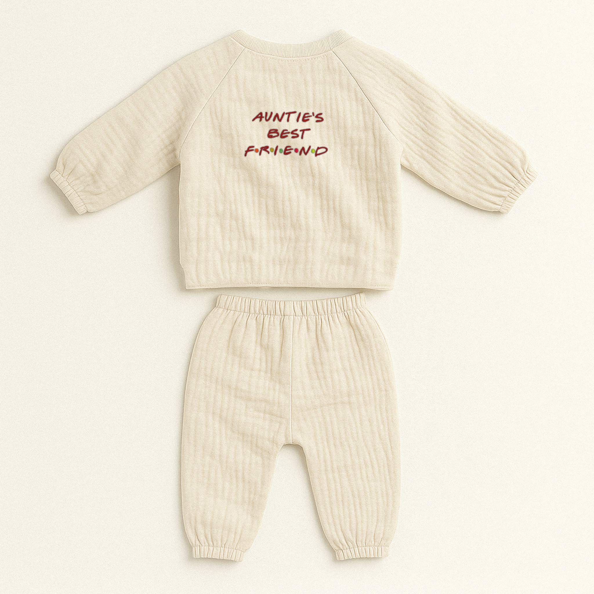 Doğal bej (ekru) renginde, müslin kumaştan yapılmış, üzerinde "Auntie's Best Friend" baskısı bulunan, yandan bağlamalı kimono üst ve pantolondan oluşan yenidoğan bebek takımı.