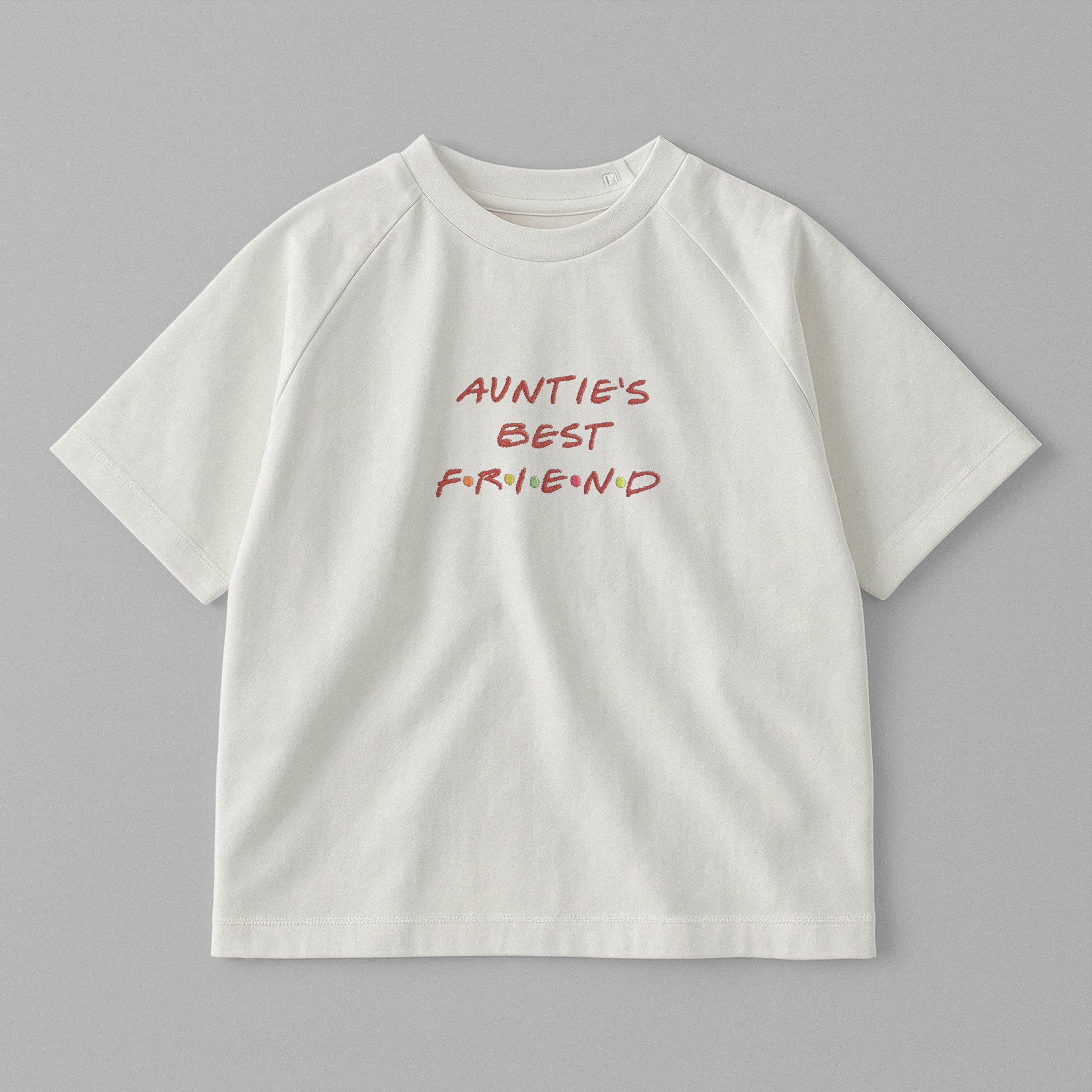 Ekru renkli, omuzdan çıtçıtlı, üzerinde Friends dizisi fontuyla kırmızı ve renkli detaylı 'AUNTIE'S BEST FRIEND' nakışı bulunan oversize pamuklu bebek tişörtü.