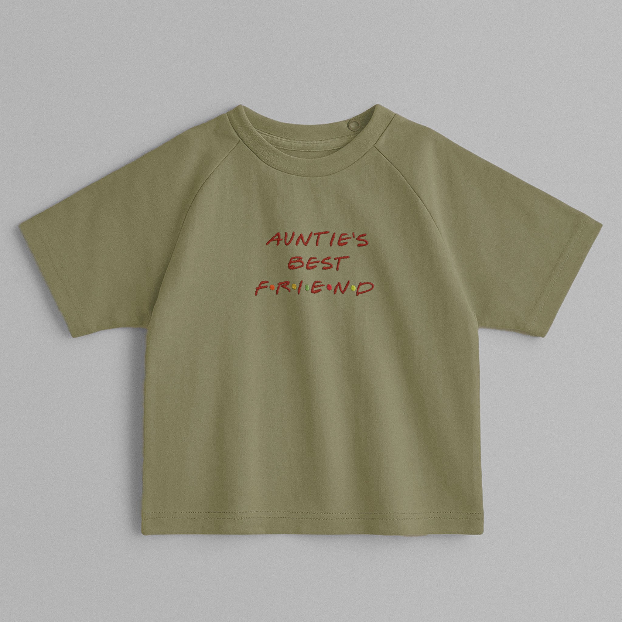Haki yeşili, omuzdan çıtçıtlı, üzerinde nostaljik Friends dizisi fontuyla 'AUNTIE'S BEST FRIEND' nakışı bulunan oversize pamuklu bebek tişörtü.