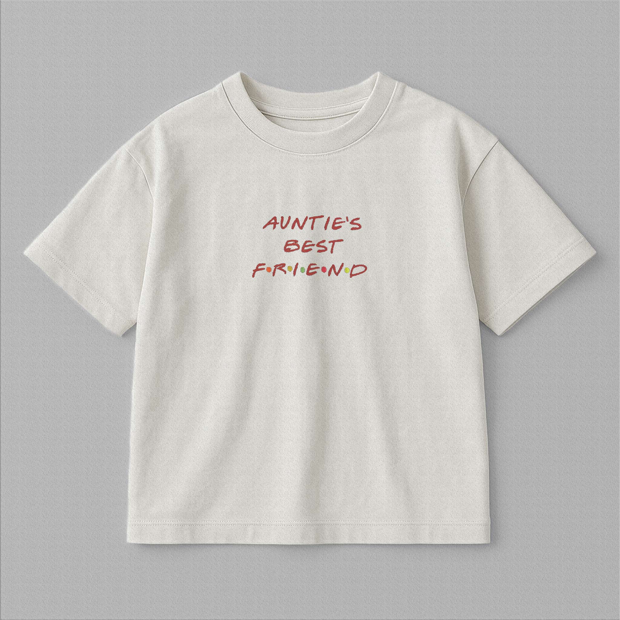 Ekru renkli, oversize kesim, üzerinde kırmızı harfler ve renkli noktalarla ikonik Friends dizisi fontunda 'AUNTIE'S BEST FRIEND' nakışı bulunan pamuklu çocuk tişörtü.