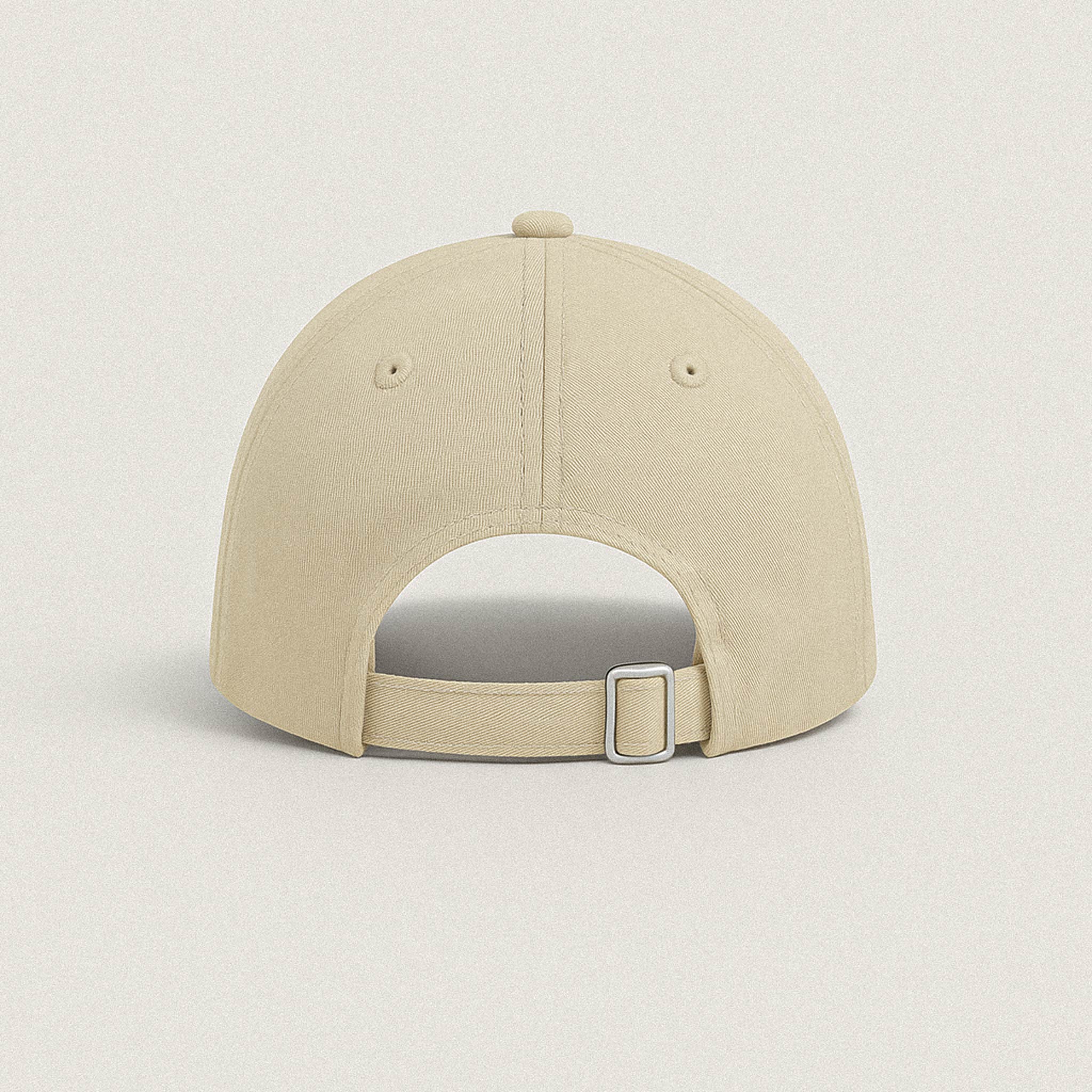 Bej renkli şapkanın arkadan görünümü, metal tokalı ayarlanabilir kayış detayı.