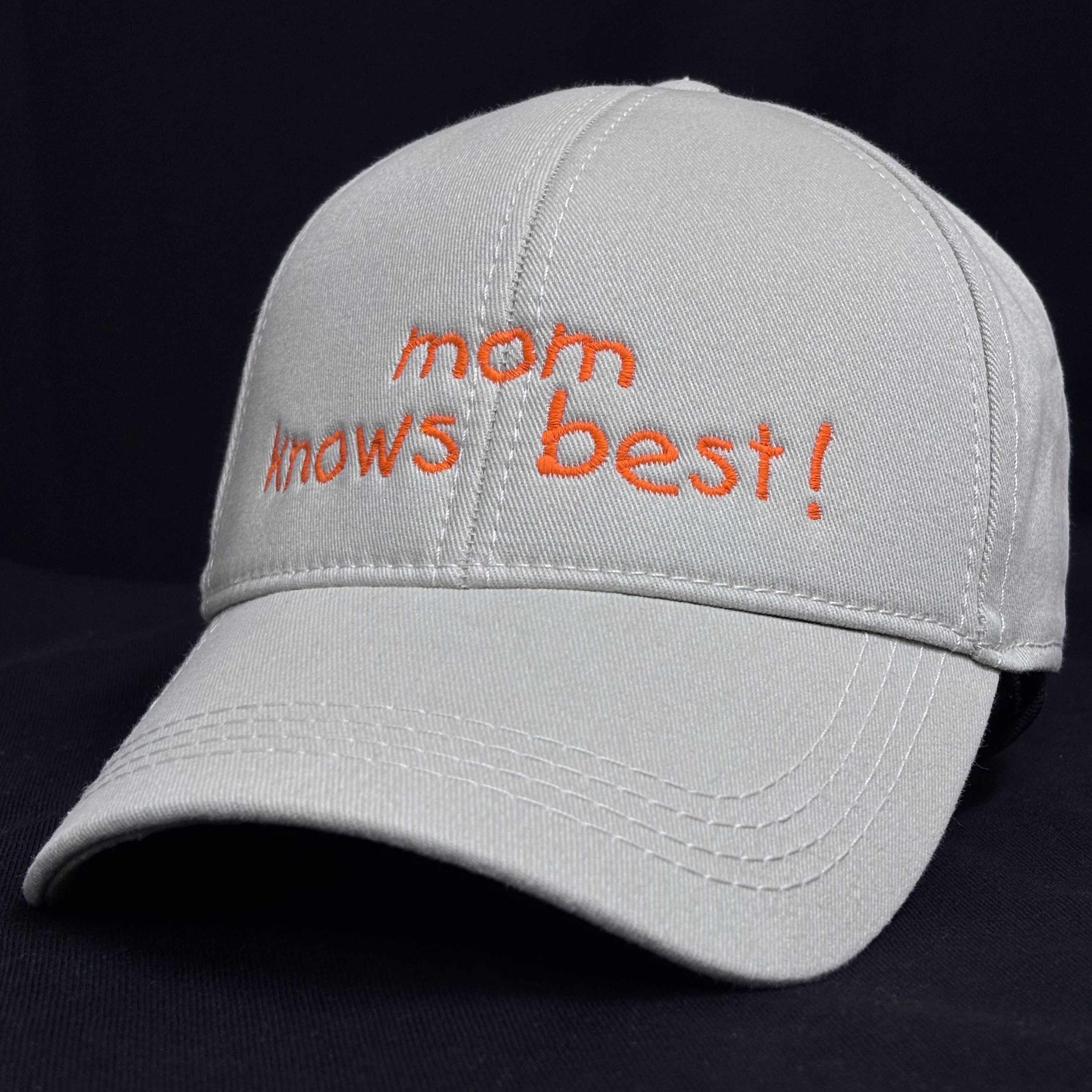 Bej (kum rengi) %100 pamuklu premium anne şapkası. Ön panelinde siyah iplikle "Mom knows best!" yazısı ve kalp nakışı, Oeko-Tex onaylı kumaş üzerine işlenmiştir. Nefes alan ve terletmeyen dokusuyla üstün konfor sunar. Hem şık hem de esprili tasarımıyla anneler için harika bir günlük giyim aksesuarı.
