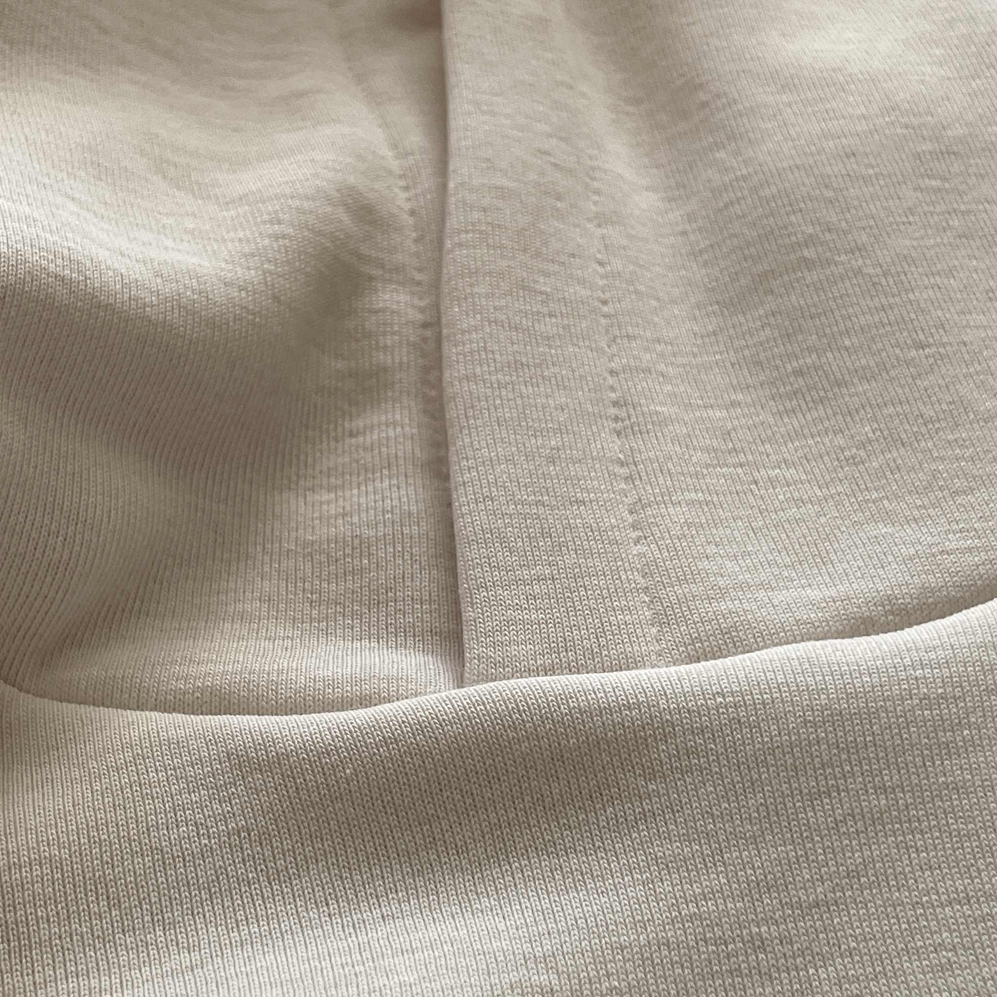 Beyaz renkli premium yetişkin hoodie modelinin yaka kısmı ve kapüşon birleşim noktasını gösteren makro detay çekimi. Kaliteli tok pamuklu kumaşın yoğun örgüsü ve kapüşonu gövdeye bağlayan pürüzsüz, sağlam dikiş işçiliği ön plana çıkmaktadır. Hem tok bir duruş hem de uzun ömürlü kullanım sunan kusursuz bir yapısal detaydır.