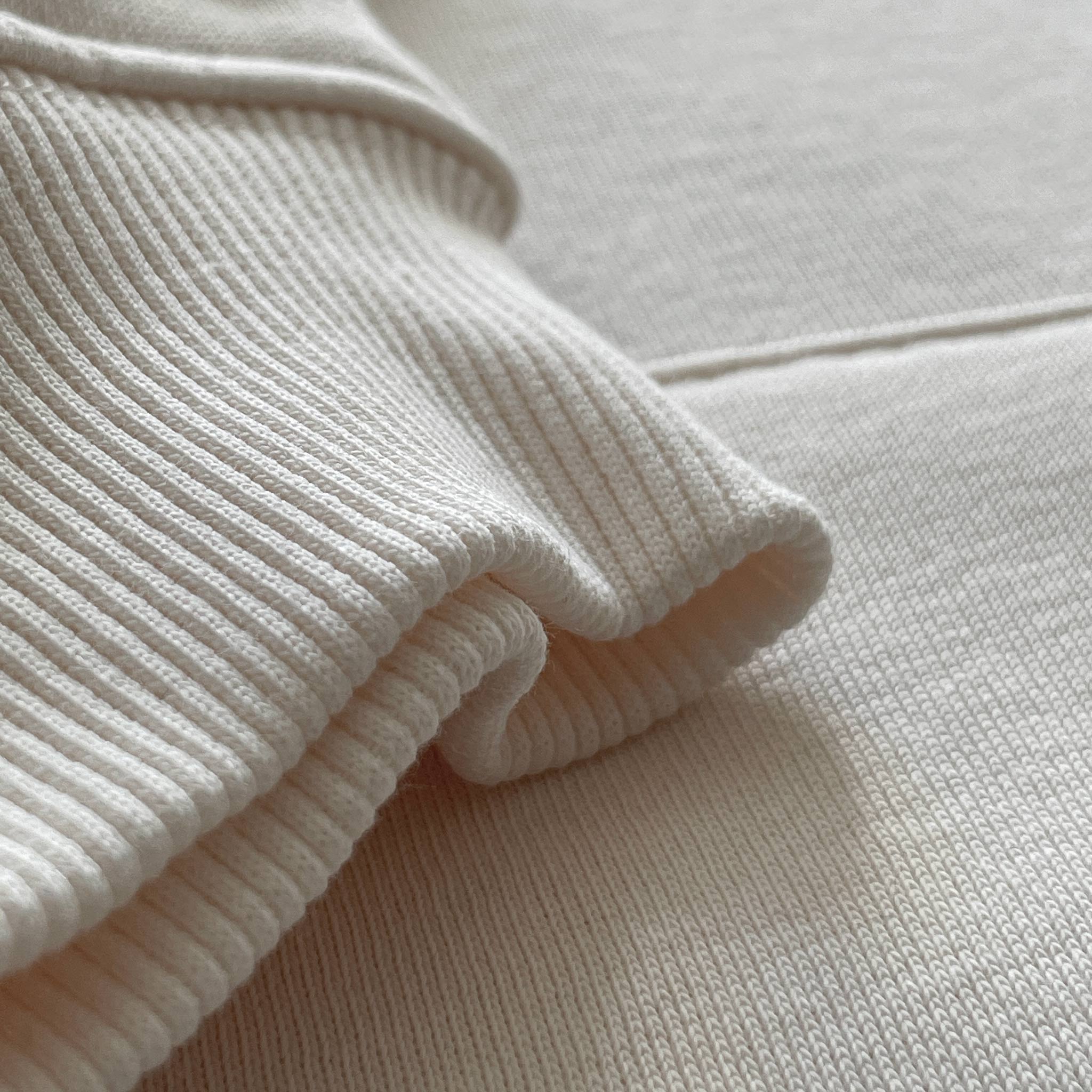 Beyaz renkli premium yetişkin hoodie modelinin esnek kol ribanasını (manşetini) gösteren makro detay çekimi. Kaliteli tok kumaşın fitilli dokusu, bileği nazikçe sararak soğuğu keser ve formunu uzun süre bozmadan korur. Üstün konforu ve dayanıklı işçiliği ön plana çıkaran yapısal detay.