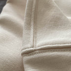 Beyaz renkli premium yetişkin hoodie modelinin omuz dikişi ile kol evi birleşim noktasını gösteren makro detay çekimi. Kaliteli tok kumaş ve kusursuz çoklu reçme dikiş işçiliği, dökümlü oversized kalıbın formunu uzun süre korumasını sağlayan yapısal sağlamlık. Şıklık ve dayanıklılık sunan temel işçilik detayı.