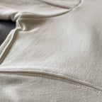 Premium beyaz hoodie modelinin tok kumaş dokusunu ve temiz dikişli kenar detayını gösteren yakın çekim. Kaliteli materyal ve minimalist tasarımın kusursuz işçiliğini vurgulayan dikiş izi. Uzun ömürlü kullanım ve şık döküm sağlayan dokunun temel detayı.