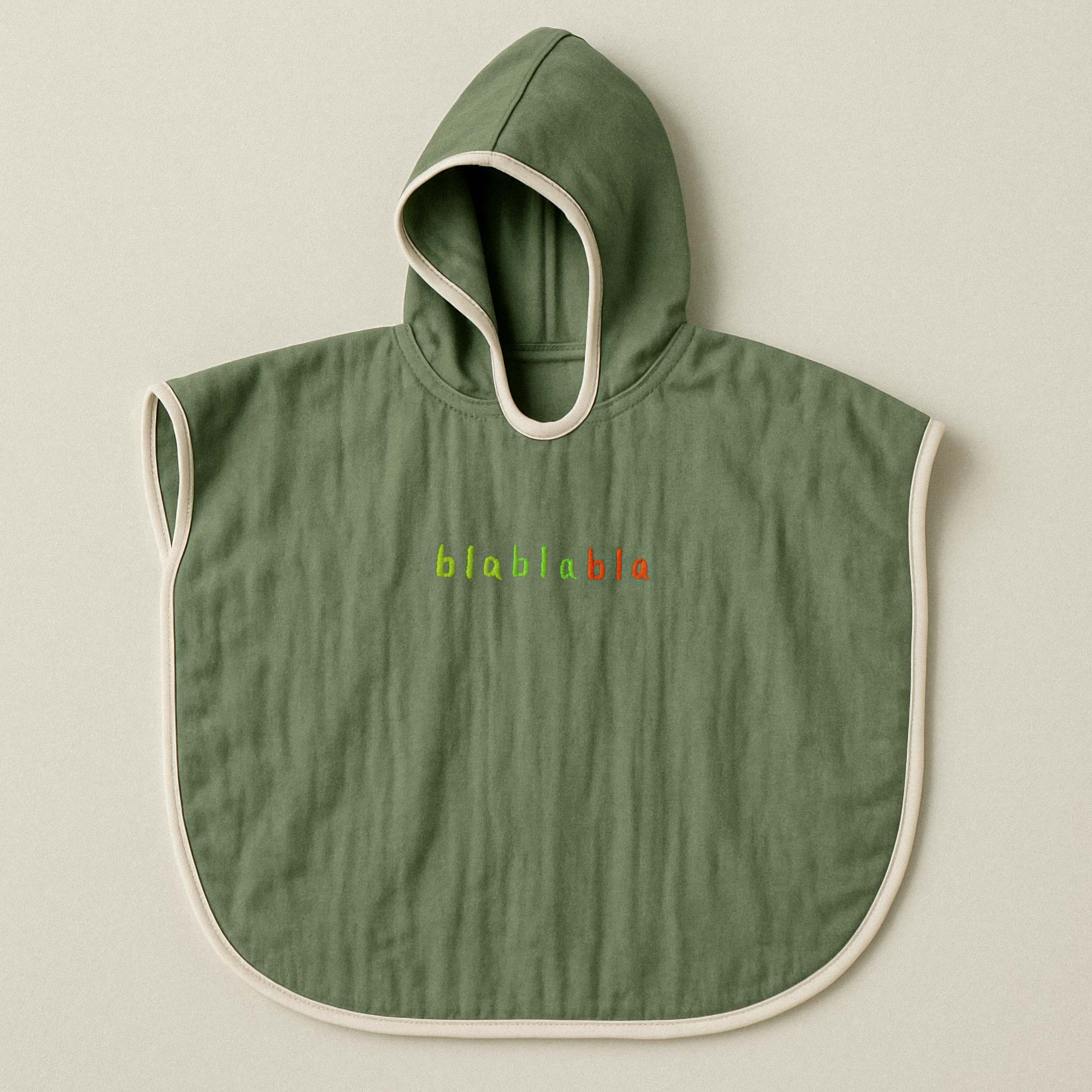 Haki yeşili renginde, kapüşonlu, müslin kumaştan bebek ve çocuk pançosu. Göğüs kısmında renkli ipliklerle "blablabla" yazısı işlenmiştir.