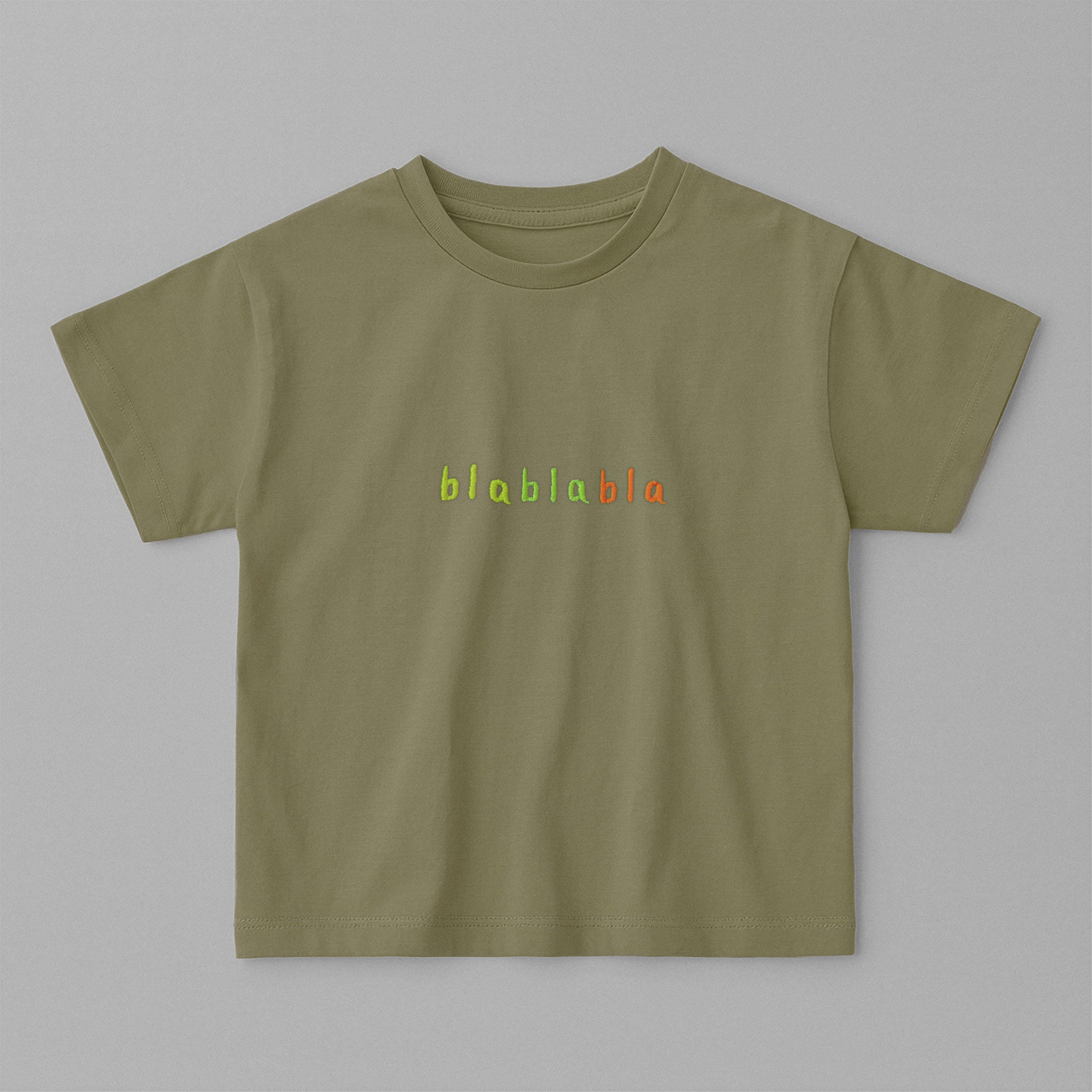 Haki yeşili, oversize kesim, 1-5 yaş için pamuklu çocuk tişörtü. Göğüs kısmında renkli ipliklerle "blablabla" nakışı bulunmaktadır.