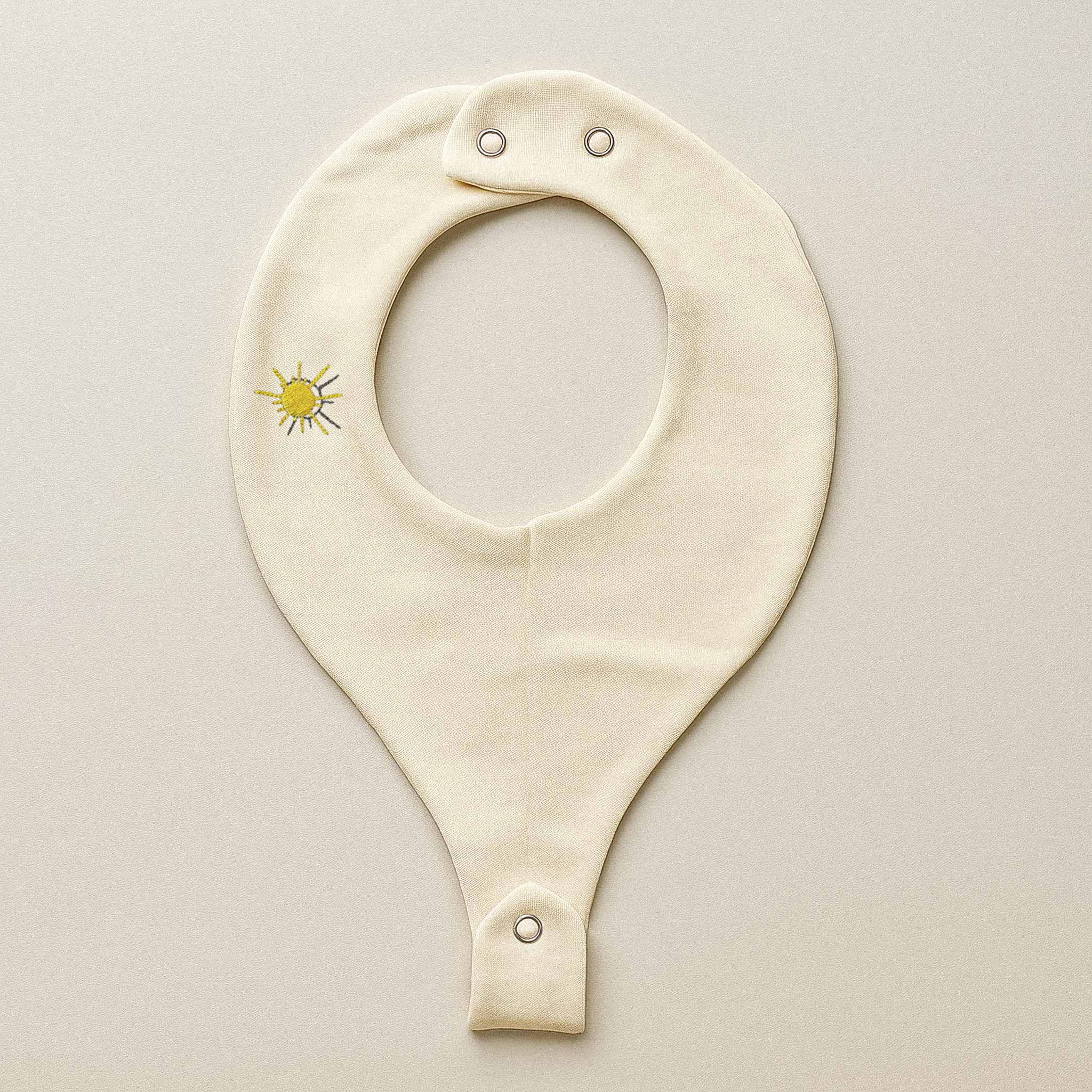 Ekru renkli, pamuklu, emzik askılı bebek mama önlüğü. Üzerinde sevimli bir güneş nakışı bulunmaktadır.