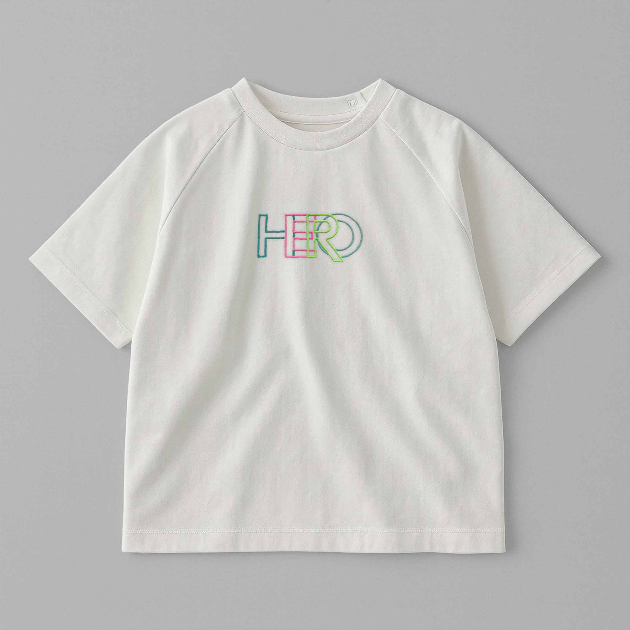 Ekru renkli, reglan kollu, arkadan çıtçıtlı bebek tişörtünün ön yüzünde renkli 'HERO' nakışı bulunmaktadır.