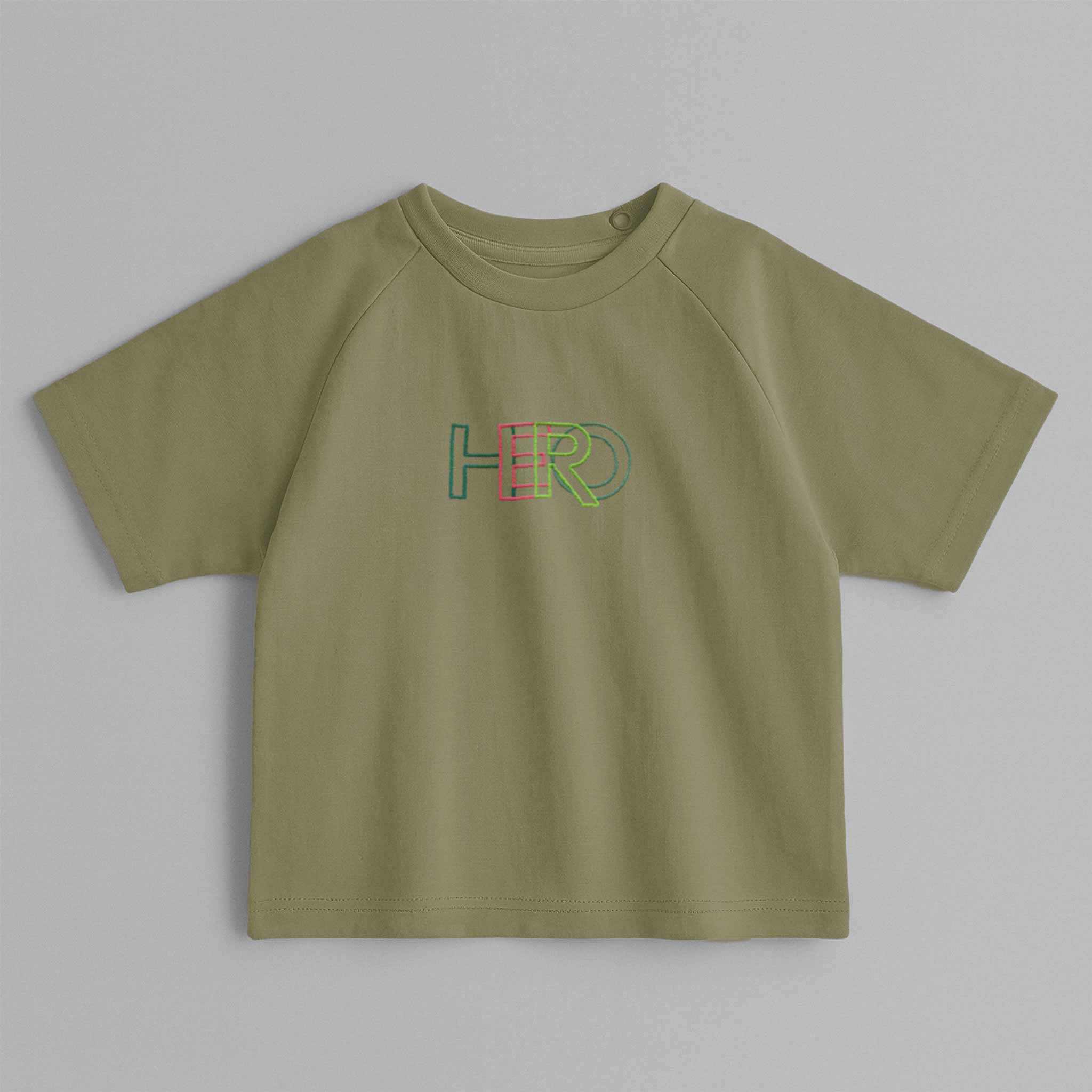 Haki yeşili, reglan kollu, arkadan çıtçıtlı bebek tişörtünün ön yüzünde renkli 'HERO' nakışı bulunmaktadır.