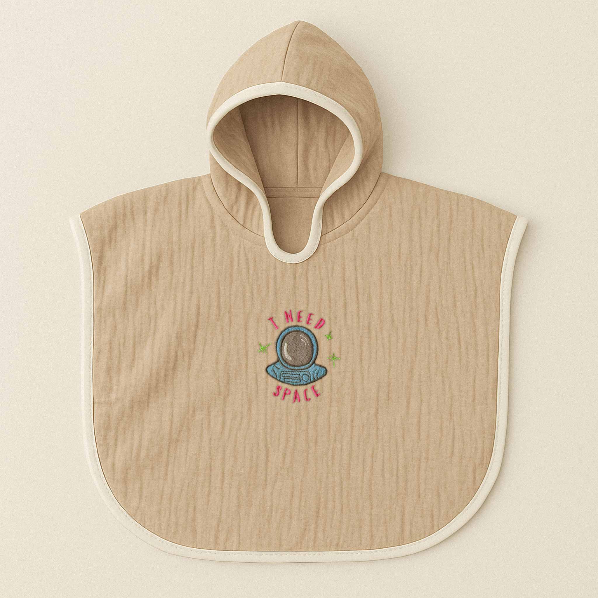 Somon rengi (bej), kapüşonlu, müslin kumaştan bebek ve çocuk pançosu. Göğüs kısmında astronot kaskı çizimi ve "I NEED SPACE" yazısı işlenmiştir.