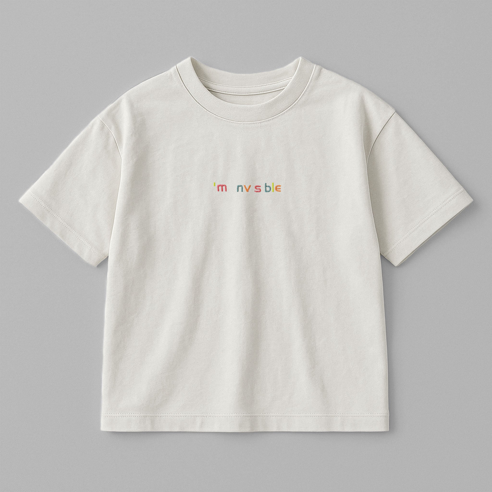 Ekru renkli, oversize kesim, 1-5 yaş için pamuklu çocuk tişörtü. Göğüs kısmında renkli ipliklerle "I'm nvsble" nakışı bulunmaktadır.