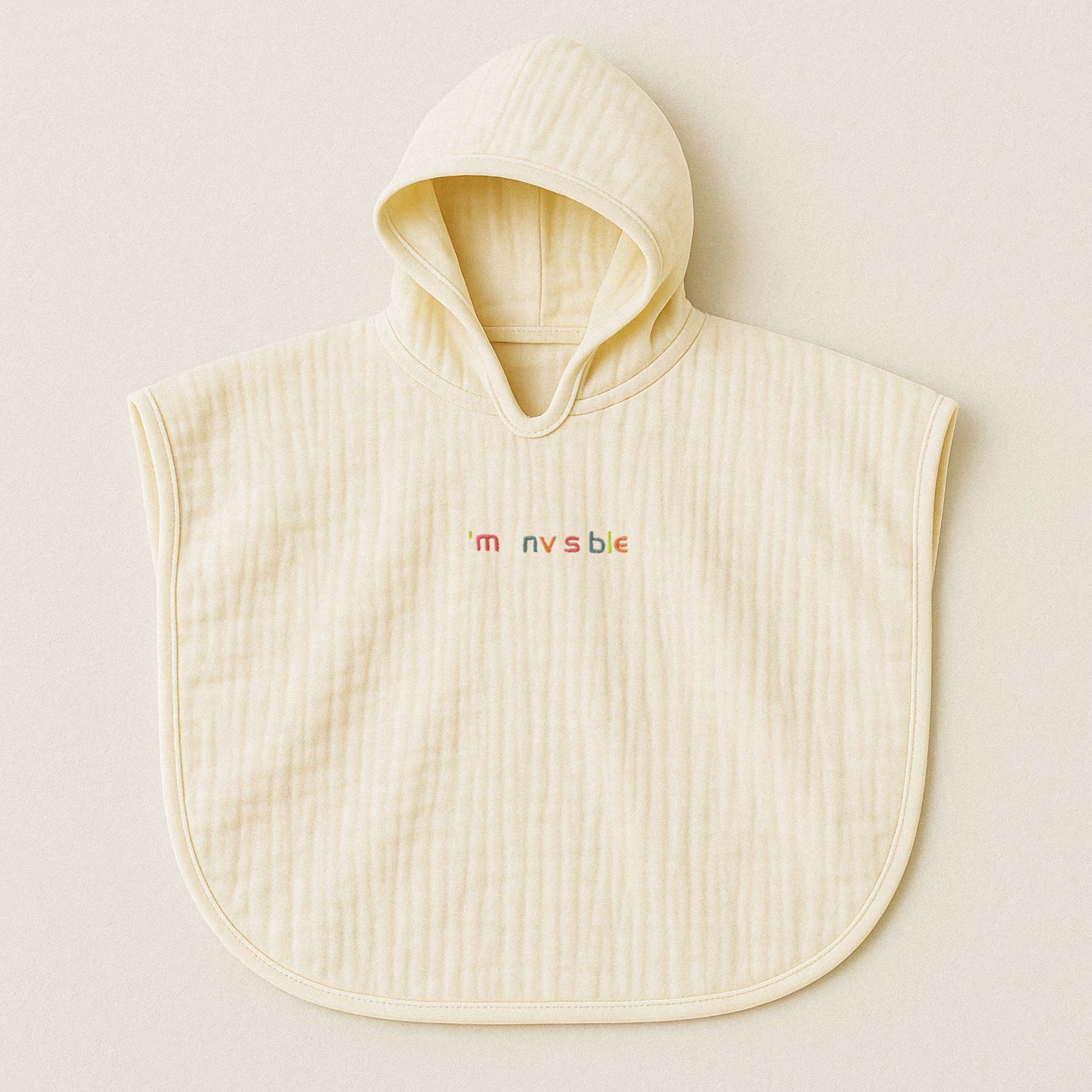 Ekru (doğal bej) renginde, kapüşonlu, müslin kumaştan bebek ve çocuk pançosu. Göğüs kısmında renkli ipliklerle "I'am nvsble" yazısı işlenmiştir.