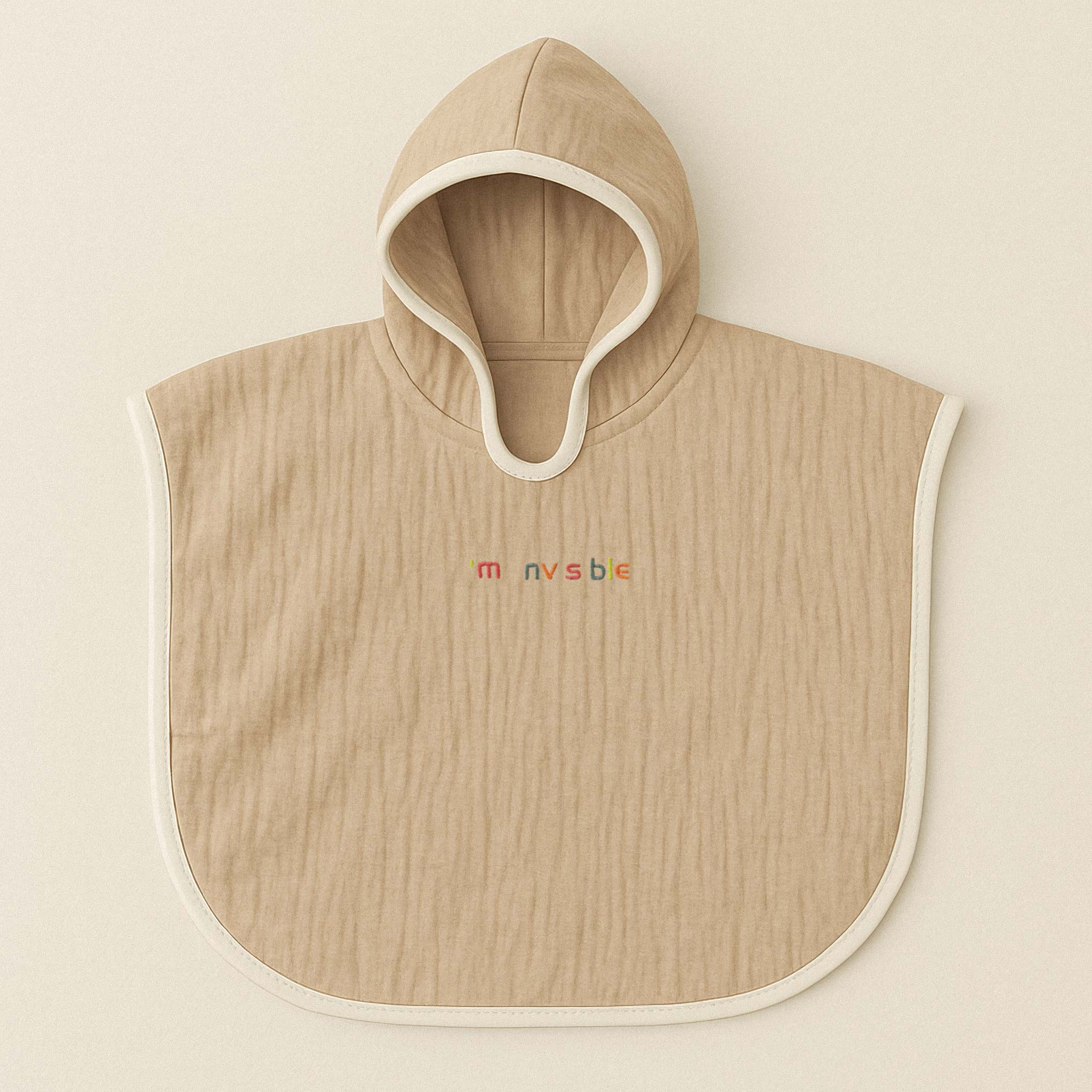 Somon rengi (bej), kapüşonlu, müslin kumaştan bebek ve çocuk pançosu. Göğüs kısmında renkli ipliklerle "I'am nvsble" yazısı işlenmiştir.