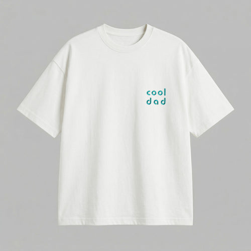 Kırık beyaz renkli %100 pamuklu Oeko-Tex sertifikalı loose fit erkek tişörtü. Sol göğüs kısmında turkuaz/petrol mavisi iplikle, modern ve yuvarlak hatlı minimal fontla işlenmiş "cool dad" nakışı yer alır. Birinci sınıf Alman nakış işçiliği ile özenle üretilmiştir. Tok duruşlu heavyweight kumaşı, nefes alan ve terletmeyen yapısıyla gün boyu rahatlık sunar. Babalar için tasarlanmış modern, sade ve premium günlük tişört tasarımı.