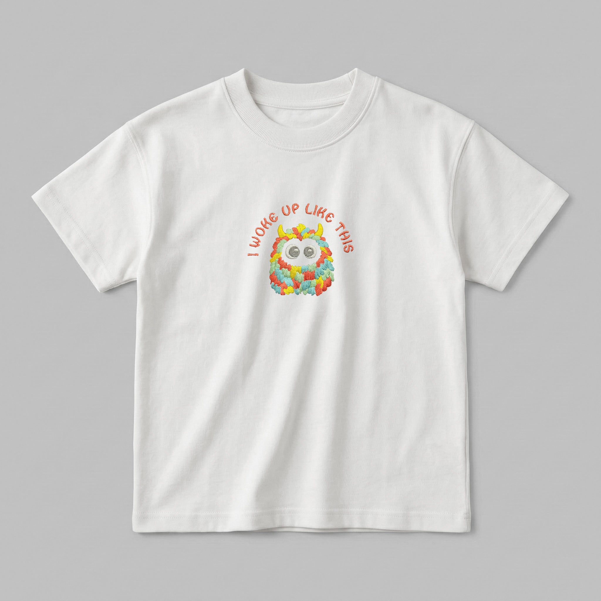Kırık beyaz renkli, %100 pamuklu Oeko-Tex sertifikalı oversize çocuk t-shirt modeli. Göğüs kısmında sevimli, renkli ve tüylü bir canavar figürü ile kiremit/turuncu tonlarında iplikle işlenmiş "I WOKE UP LIKE THIS" nakışı yer alır. Birinci sınıf Alman nakış işçiliği ile özenle üretilmiştir. Tok duruşlu heavyweight kumaşı, nefes alan ve terletmeyen yapısıyla çocukların hassas cildine uygun, eğlenceli ve premium günlük t-shirt tasarımı.