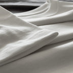 Kırık beyaz (ekru) premium yetişkin t-shirt modelinin kol ucundaki kusursuz çoklu reçme dikiş işçiliğini ve tok kumaş dokusunu gösteren yakın çekim. Kaliteli materyal ve minimalist tasarımın kusursuz işçiliğini vurgulayan temiz dikiş izi. Dayanıklı ve dökümlü yapıyı ön plana çıkaran yapısal detay.
