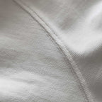 Kırık beyaz (ekru) renkli premium yetişkin t-shirt modelinin kol dikişini ve tok pamuklu kumaş dokusunu gösteren yakın çekim. Kaliteli materyal ve minimalist tasarımın kusursuz işçiliğini vurgulayan temiz dikiş izi. Ağır gramajlı (heavyweight) tok kumaşın yoğun örgüsü ve premium hissi.