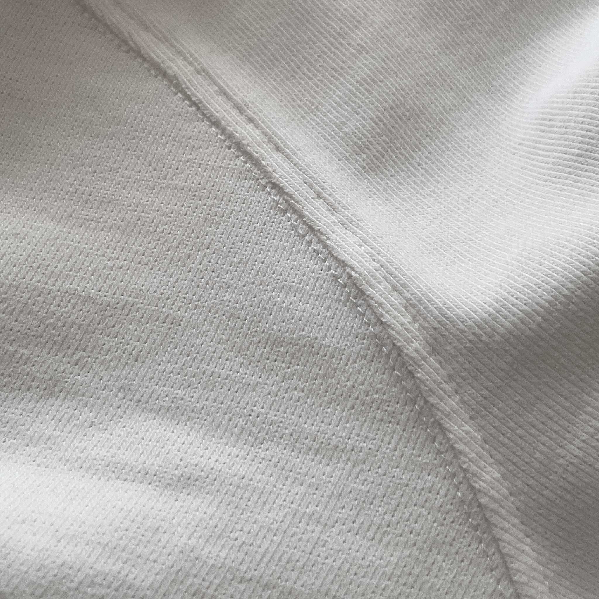 Kırık beyaz (ekru) renkli premium yetişkin t-shirt modelinin kol dikişini ve tok pamuklu kumaş dokusunu gösteren yakın çekim. Kaliteli materyal ve minimalist tasarımın kusursuz işçiliğini vurgulayan temiz dikiş izi. Ağır gramajlı (heavyweight) tok kumaşın yoğun örgüsü ve premium hissi.