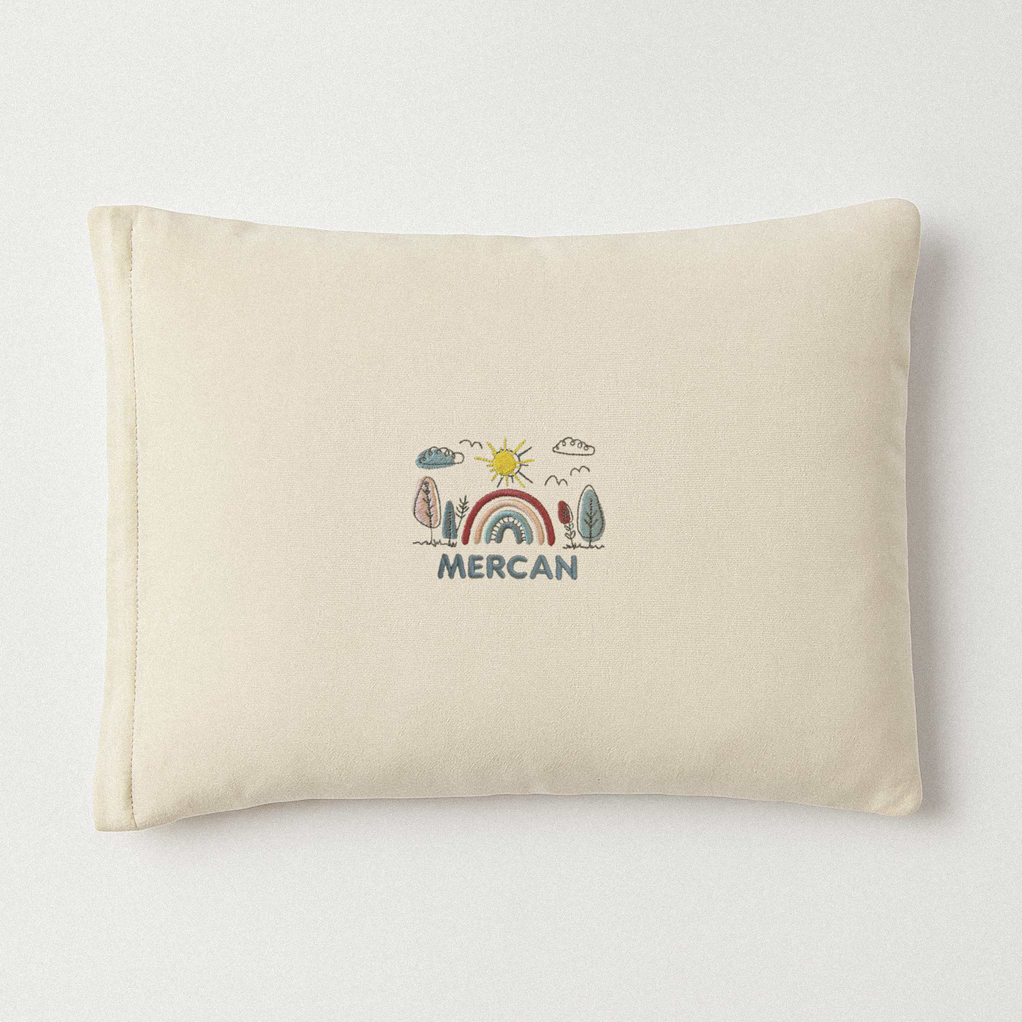 Ekru renkli, pamuklu bebek yastık kılıfı. Üzerinde gökkuşağı manzarası ve altında 'Mercan' ismi nakışla işlenmiştir (İsim kişiselleştirilebilir).