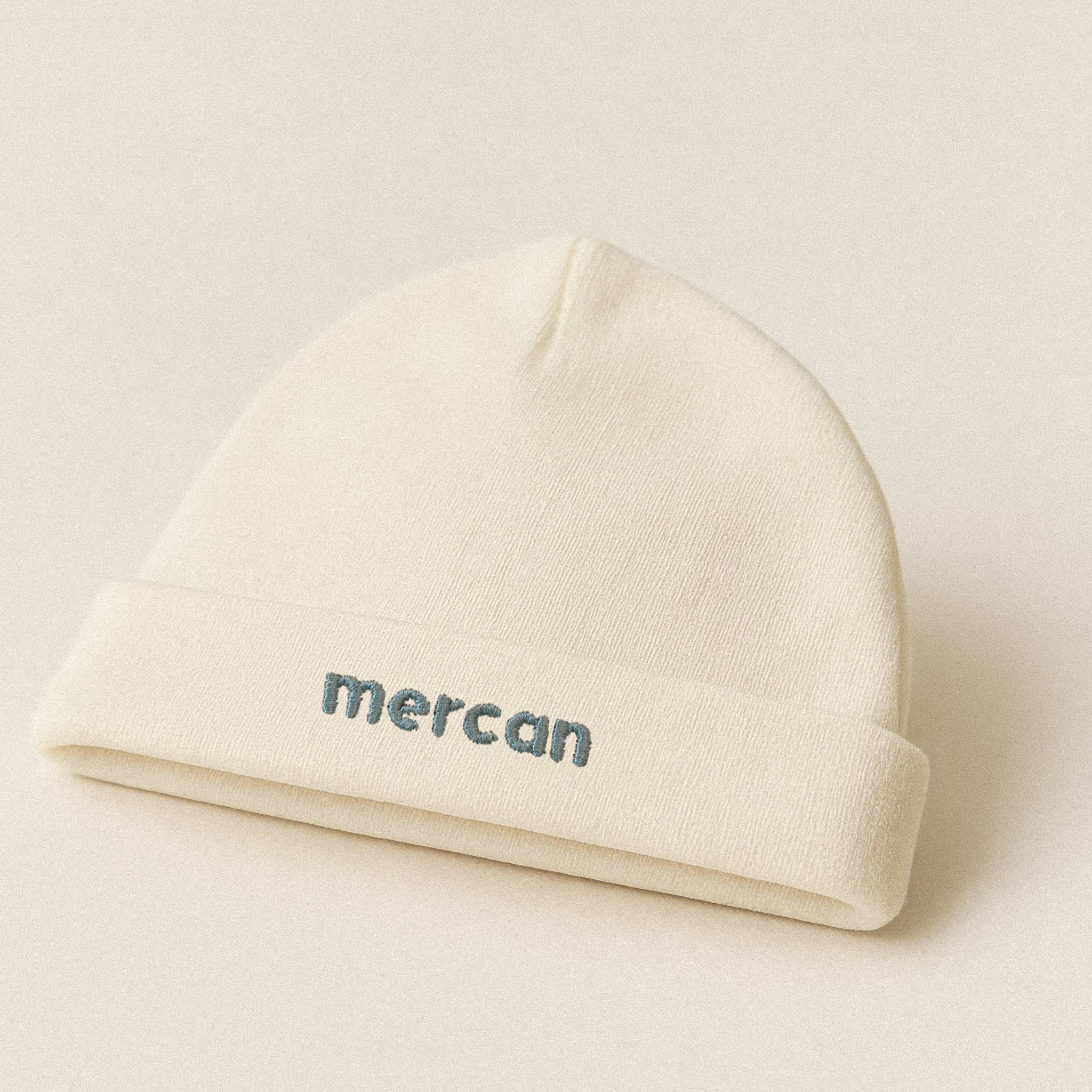 Ekru renkli, %100 pamuklu yenidoğan bebek beresi. Katlanan kısmında mavi iplikle 'Mercan' ismi nakışla işlenmiştir (İsim kişiselleştirilebilir).
