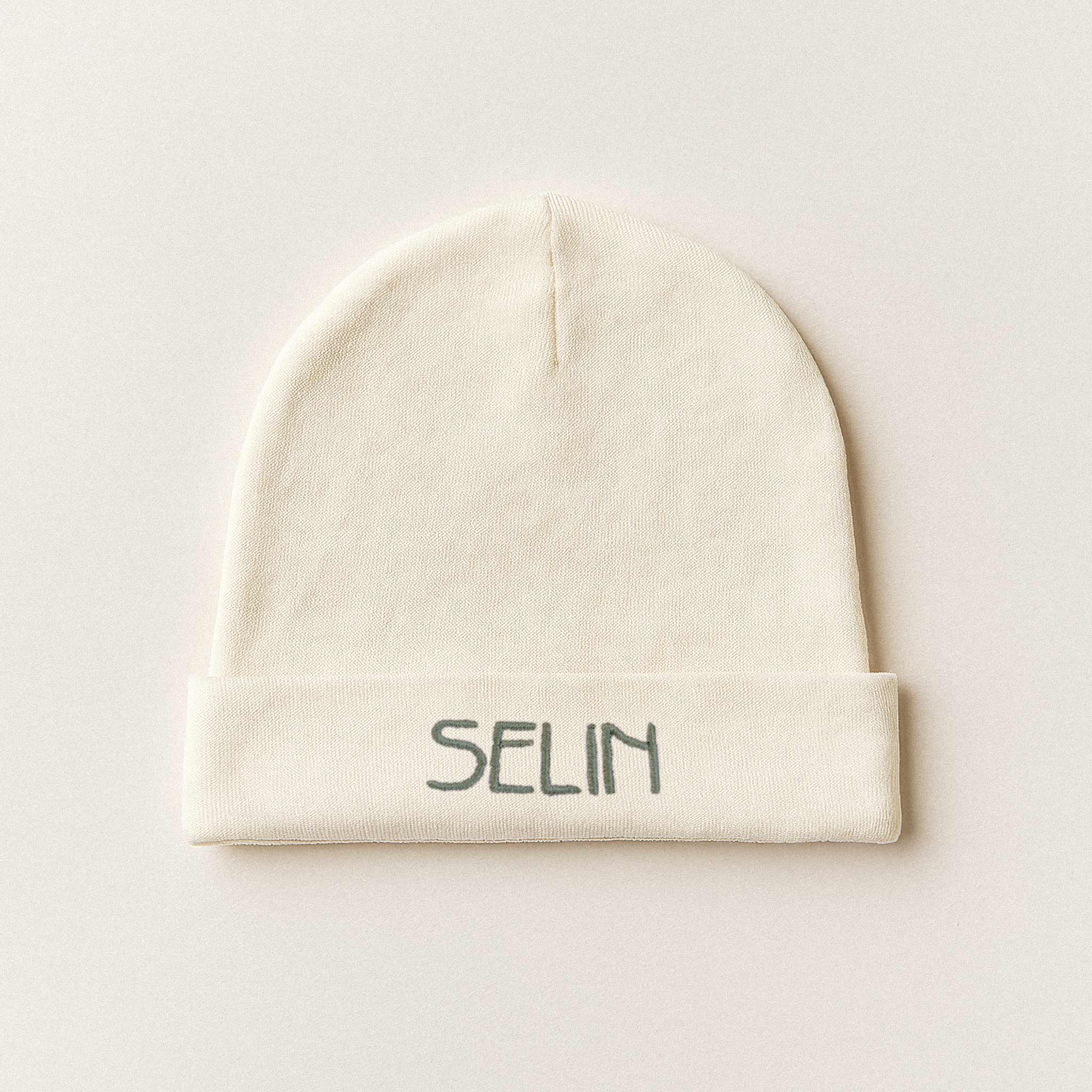 Ekru renkli, %100 pamuklu yenidoğan bebek beresi. Katlanan kısmında 'Selin' ismi nakışla işlenmiştir (İsim kişiselleştirilebilir).