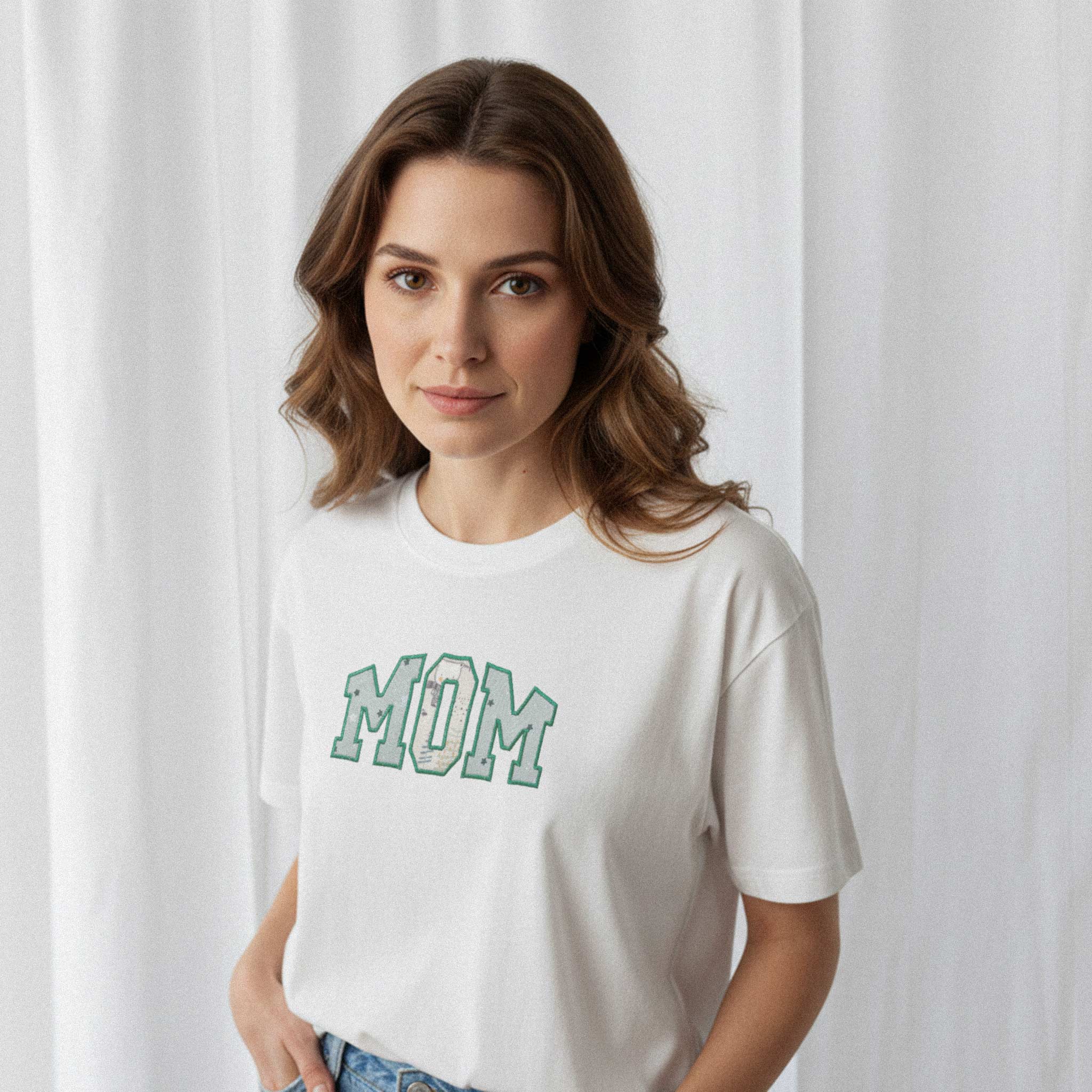 Kadın modelin üzerinde duran ekru renkli, oversize kesim, kişiye özel 'MOM' aplikeli Bona Pera anne tişörtünün yakın plan portre fotoğrafı.