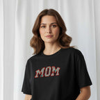 Kadın modelin üzerinde duran siyah renkli, oversize kesim, kişiye özel 'MOM' aplikeli Bona Pera anne tişörtünün yakın plan portre fotoğrafı.