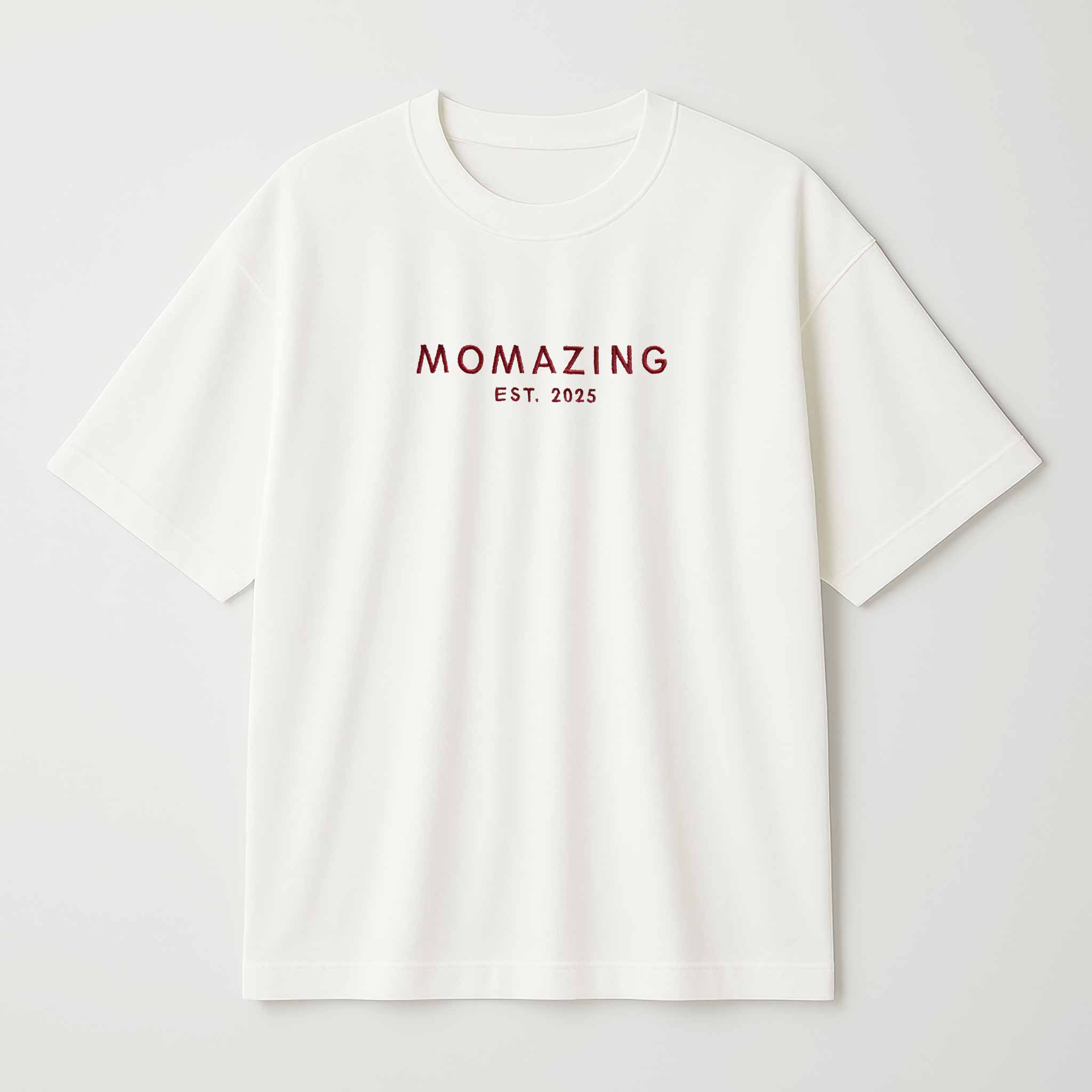 Krem (ekru) renkli, oversize kesim, Bona Pera marka pamuklu anne tişörtü. Göğüs kısmında kırmızı iplikle "MOMAZING EST. 2025" yazısı nakışla işlenmiştir.