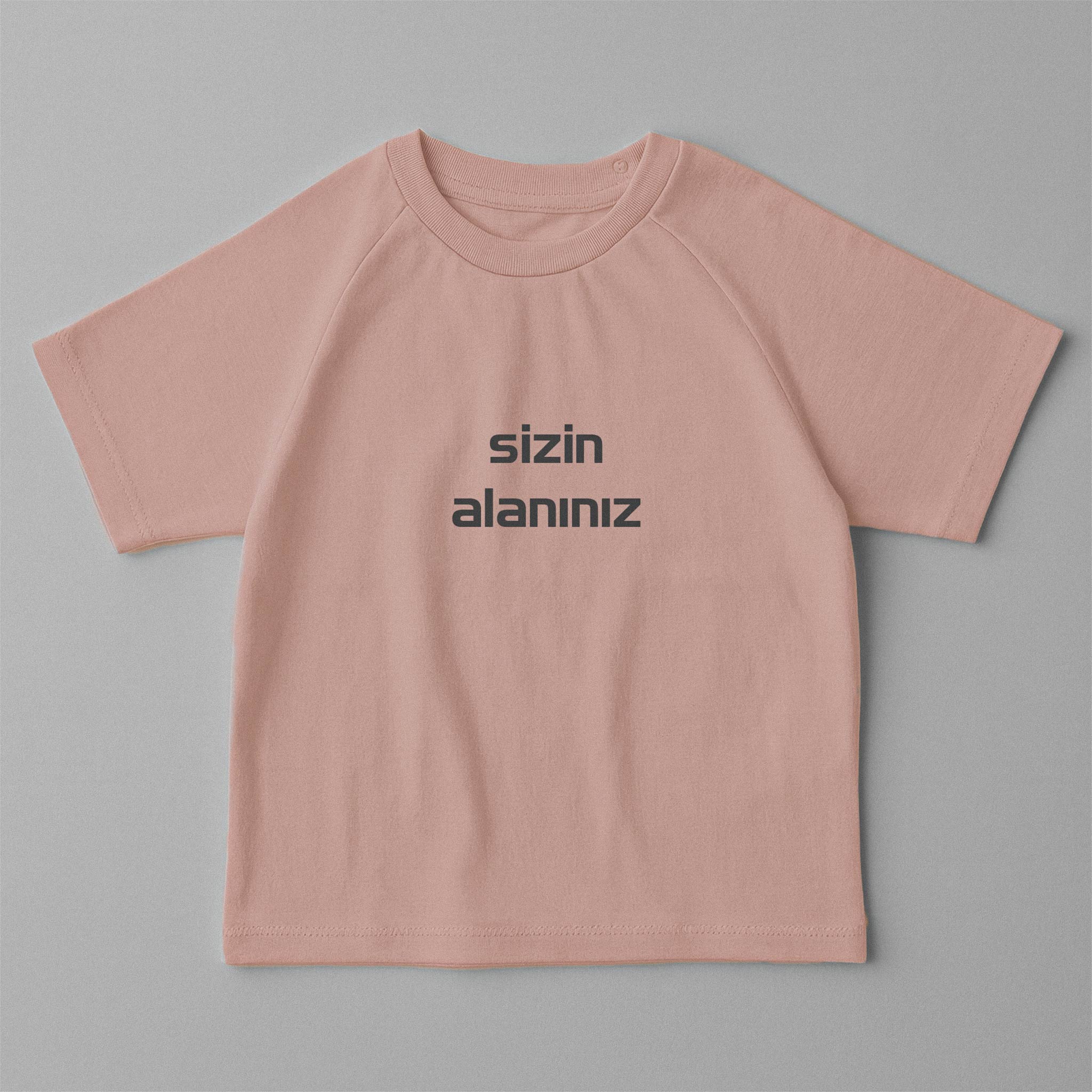 Gül kurusu (pembe) renkli, reglan kollu, omuzdan çıtçıtlı, üzerine istenilen yazının nakışla işlenebildiği pamuklu oversize bebek tişörtü.