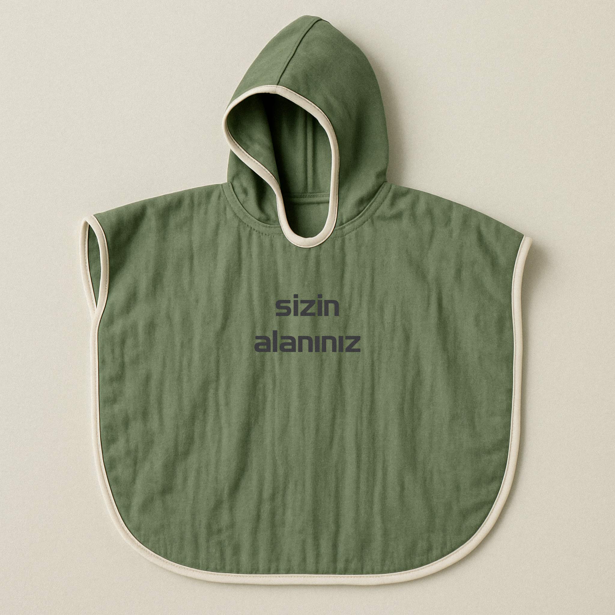 Haki yeşili renginde, kapüşonlu, müslin kumaştan, üzerine istenilen yazının nakışla işlenebildiği bebek ve çocuk pançosu.