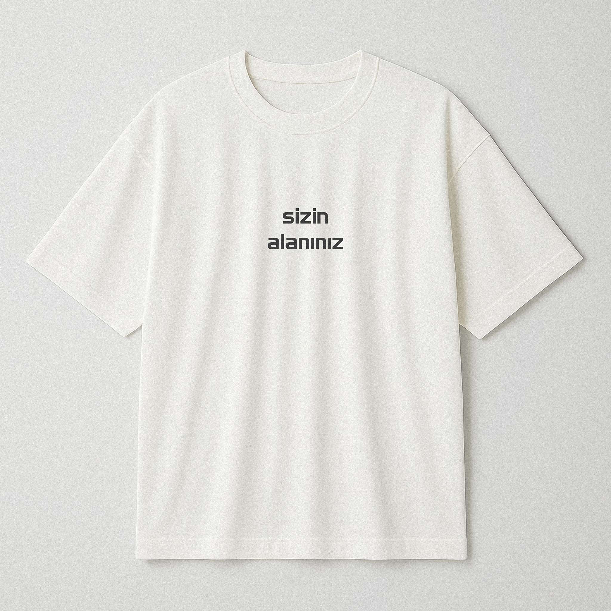 Ekru (kırık beyaz) renkli, oversize kesim, üzerine istenilen yazının nakışla işlenebildiği pamuklu unisex yetişkin tişörtü.
