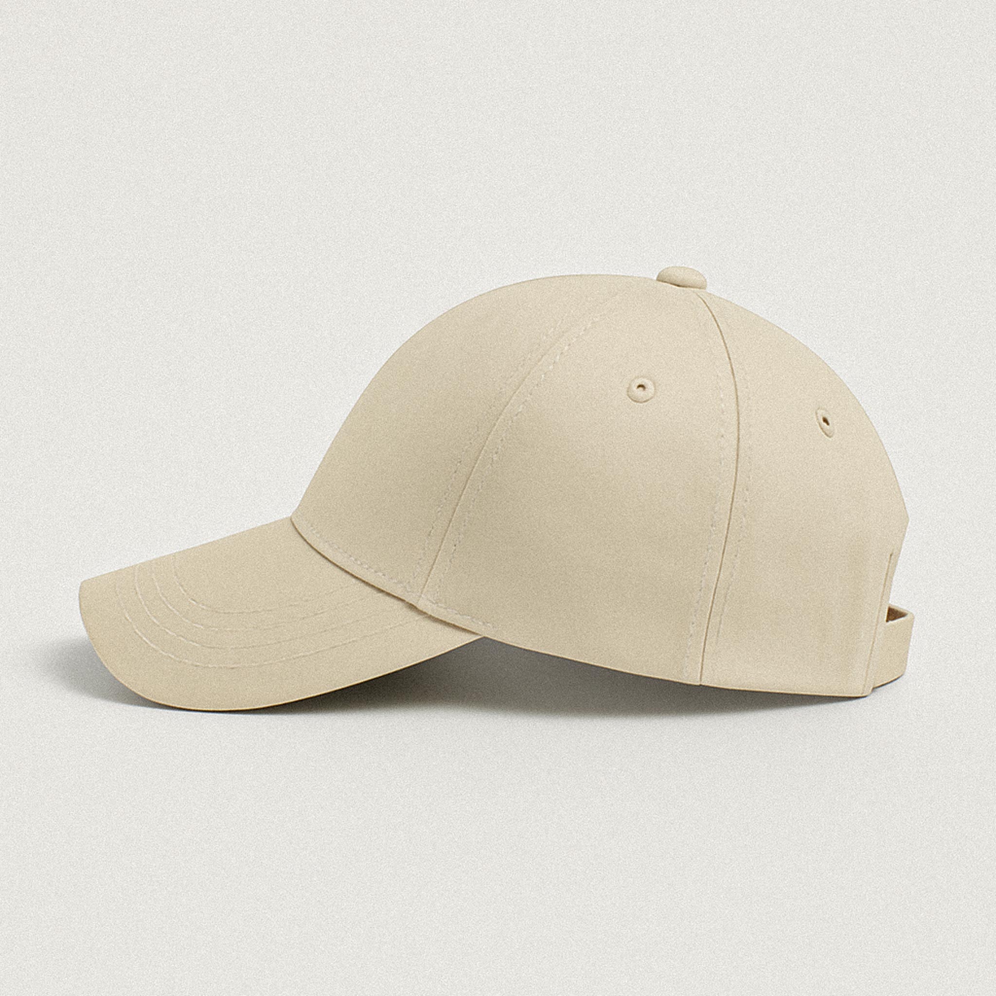 Yan profilden görünen, kavisli siperlikli ve kişiselleştirilebilir bej renkli unisex şapka.