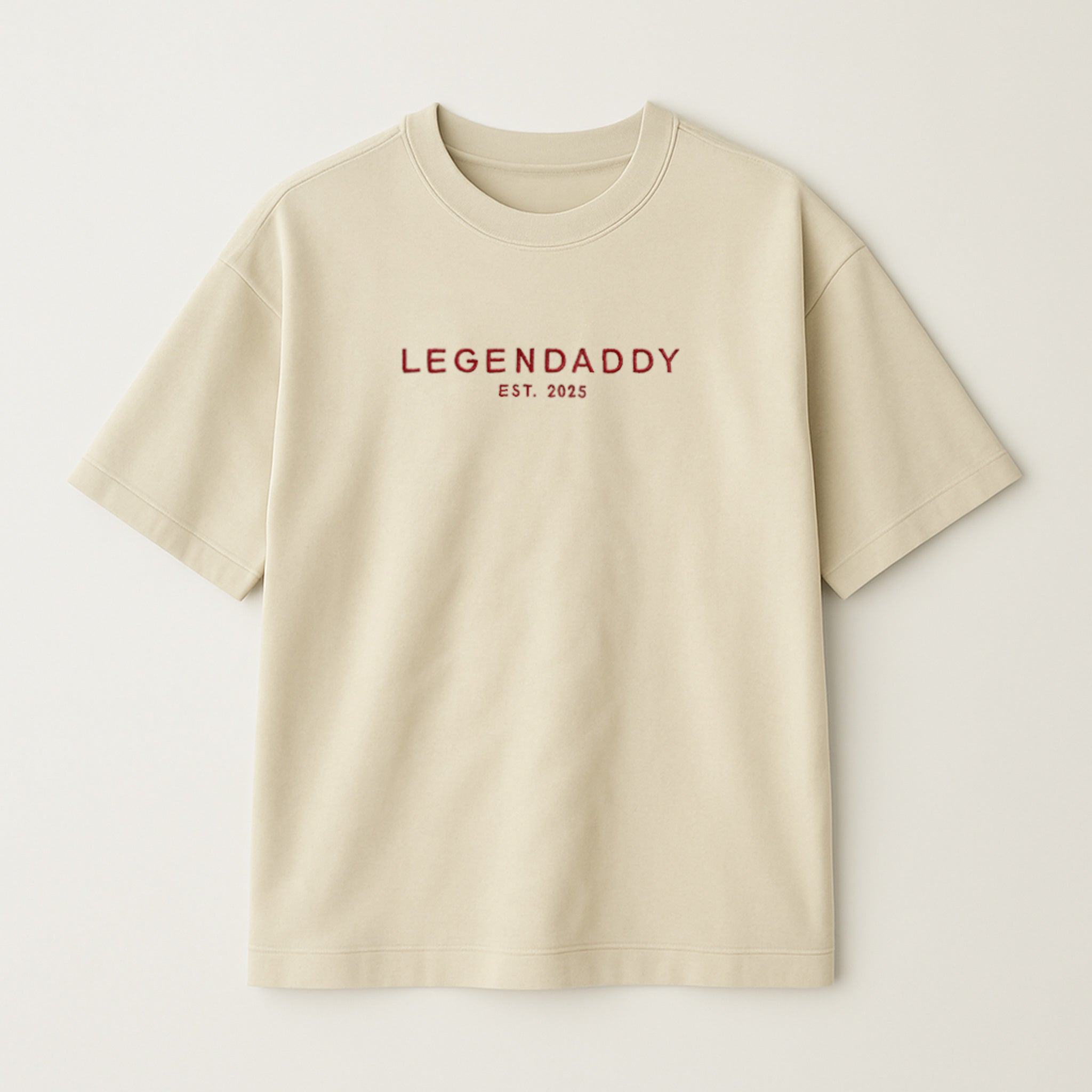 Bej renkli, oversize kesim, göğüs kısmında kırmızı iplikle 'LEGENDADDY' yazısı ve altında kişiselleştirilebilir 'EST. YYYY' tarihi nakışla işlenmiş pamuklu unisex tişört.