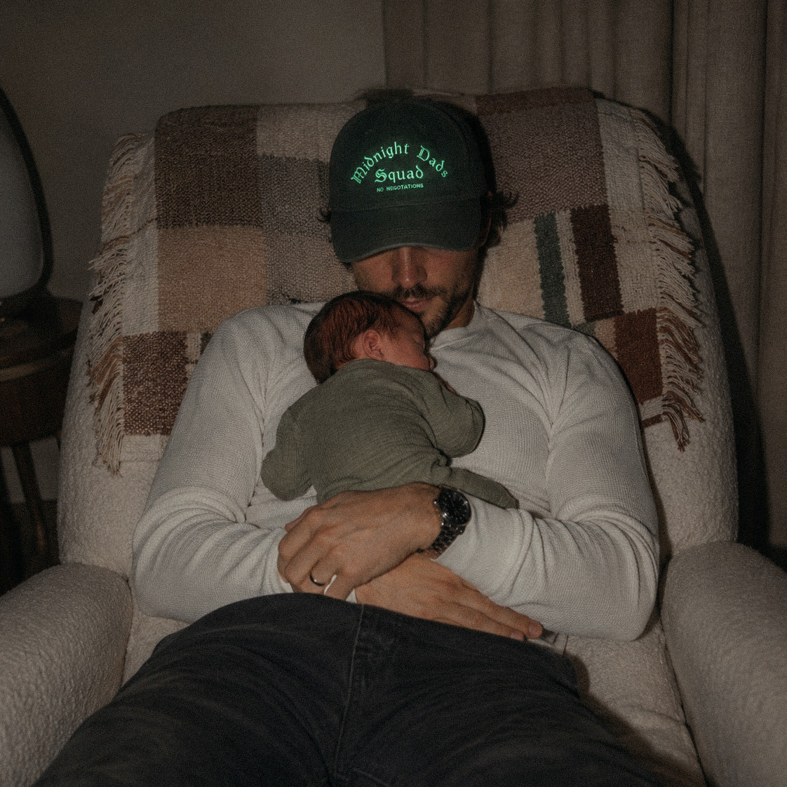 Koyu yeşil renkli %100 pamuklu premium beyzbol şapkası. Ön kısmında açık yeşil/neon renk iplikle işlenmiş "Midnight Dads SQUAD no negotiations" nakışı yer alır. Yenidoğan bebekli babaların gece mesaisine atıfta bulunan esprili tasarımın, loş ışıkta uyku anını yansıtan lifestyle ürün çekimi.