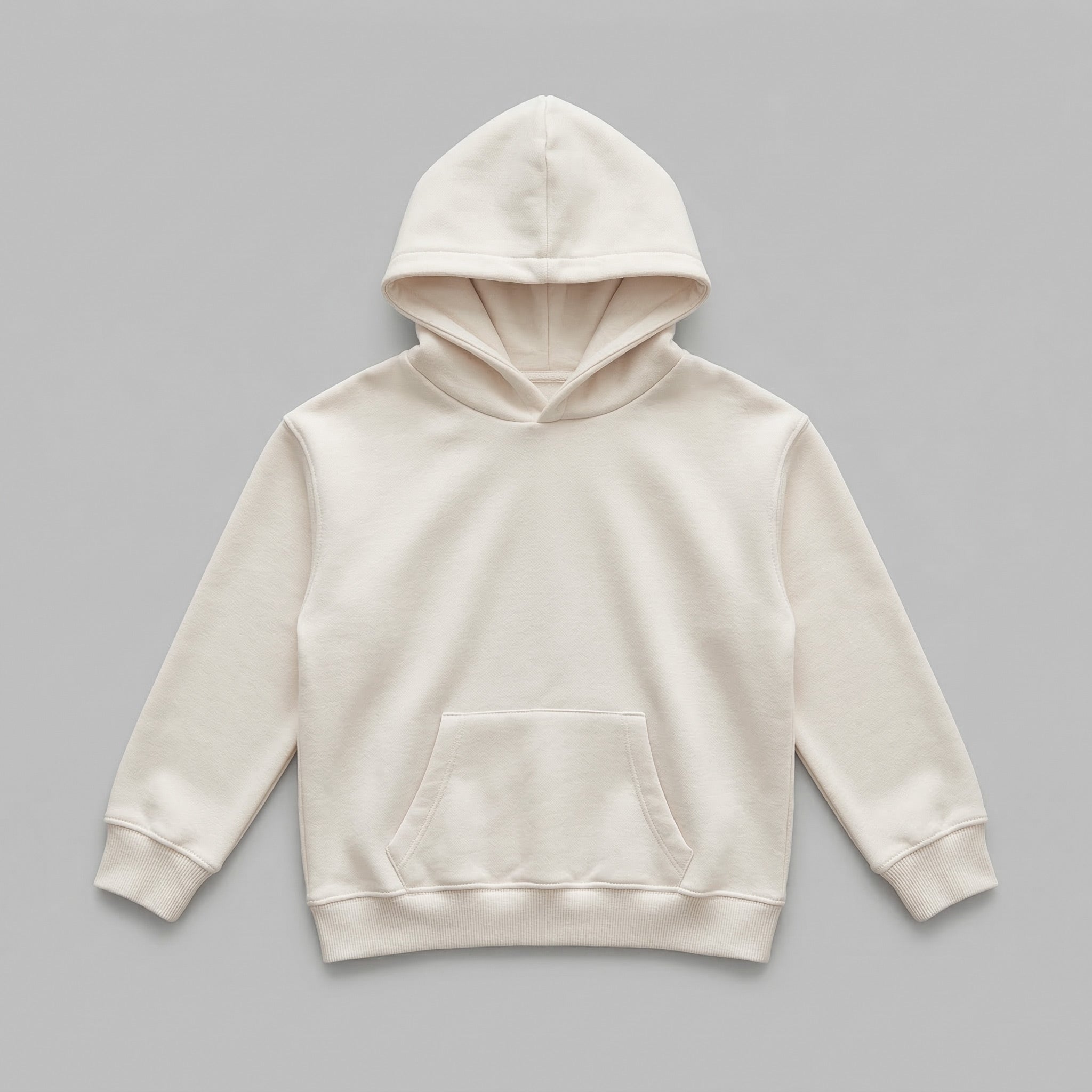 Yeni tasarımlarınızı müşterilerinize sunmak için hazırlanan krem renkli boş çocuk hoodie mockup modeli. %65 pamuklu rüzgar geçirmeyen dış yüzeyi ve içi kalın şardonlu polar dokusu, çocukları soğuktan korurken nefes alan yapısıyla terlemeyi engeller. Oeko-Tex onaylı bu konforlu tasarım, 2-7 yaş için tasarlanmış dayanıklı kanguru cebi ve kalın ribana etek ucuyla öne çıkar. Kendi nakış veya baskı çalışmalarınız için pürüzsüz, kaliteli ve uzun ömürlü bir zemin sunar.