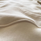 Krem renkli şardonlu çocuk hoodie modelinin kanguru cep birleşim yerindeki kusursuz ve sağlam üst dikişlerini gösteren detay fotoğrafı. Çocukların dışarıda güvenle oyun oynarken ellerini ısıtabileceği pratik cep tasarımı. Nefes alan pamuklu yapısı ve soğuğu geçirmeyen kalın kışlık kumaşıyla Oeko-Tex onaylı bu çocuk sweatshirt, formunu koruyan esnek dokusuyla soğuk havalarda maksimum rahatlık sağlar. Terletmeyen iç yüzeyi sayesinde hareketli çocukların kışlık gardırobu için ideal bir parçadır.