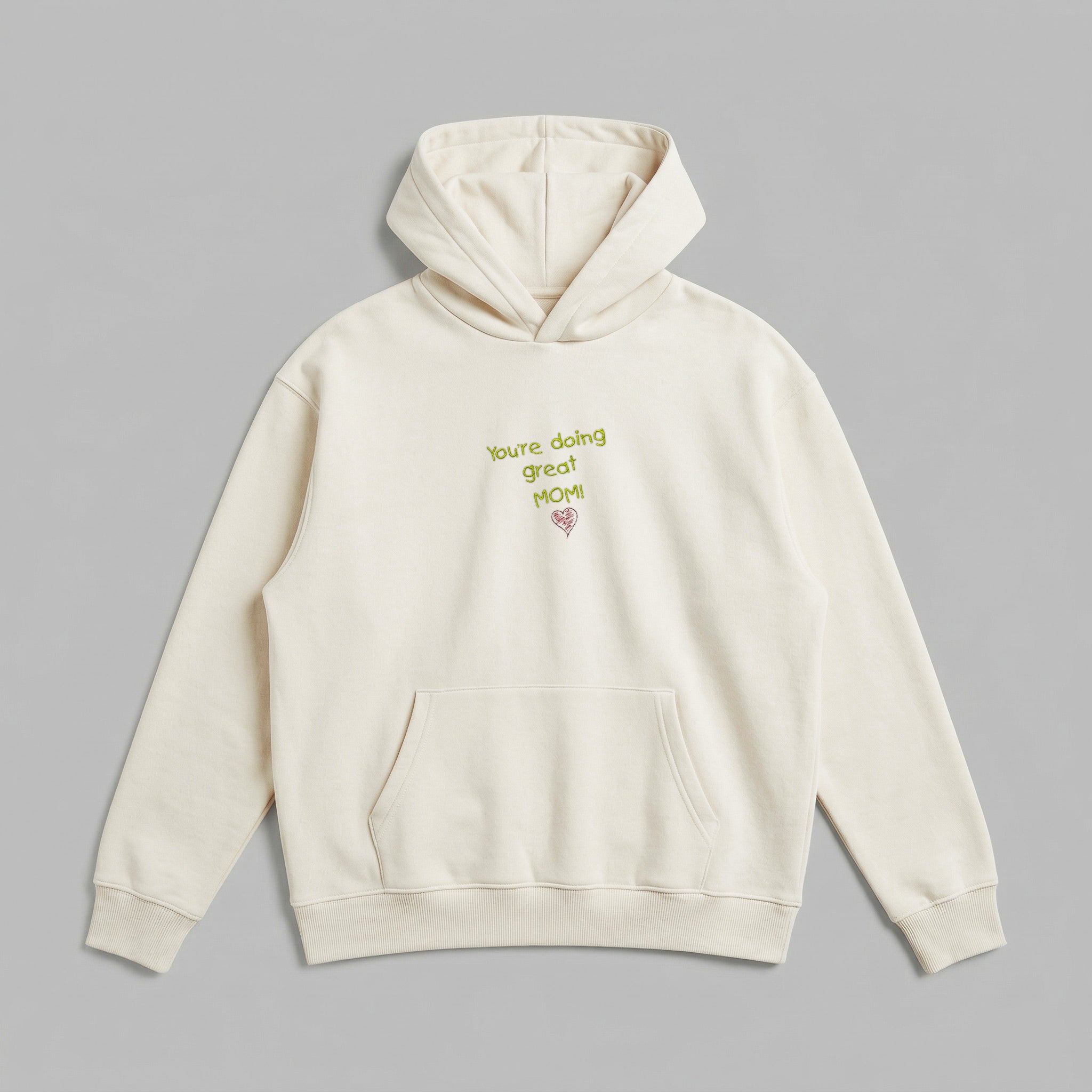 Günlük hayatta annelerin konforunu artırmak için özel hazırlanan, krem renkli premium kadın hoodie modeli. Yüksek kalite Alman nakış tekniği kullanılarak eklenen You're doing great MOM! mesajı ve kalp detayıyla öne çıkar. %65 pamuklu içeriği ve içi şardonlu polar dokusu sayesinde soğuğa karşı üstün koruma sağlarken, nefes alabilen yapısıyla gün boyu rahatlık sunar. Geniş kanguru cebi ve kalın ribana etek ucuyla uzun ömürlü, Oeko-Tex onaylı harika bir günlük giyim alternatifidir.