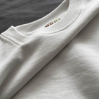 Ekru renkli premium oversize tişörtün katlanmış halini, yumuşak tok kumaş dokusunu ve kalın fitilli yaka detayını gösteren ürün fotoğrafı.