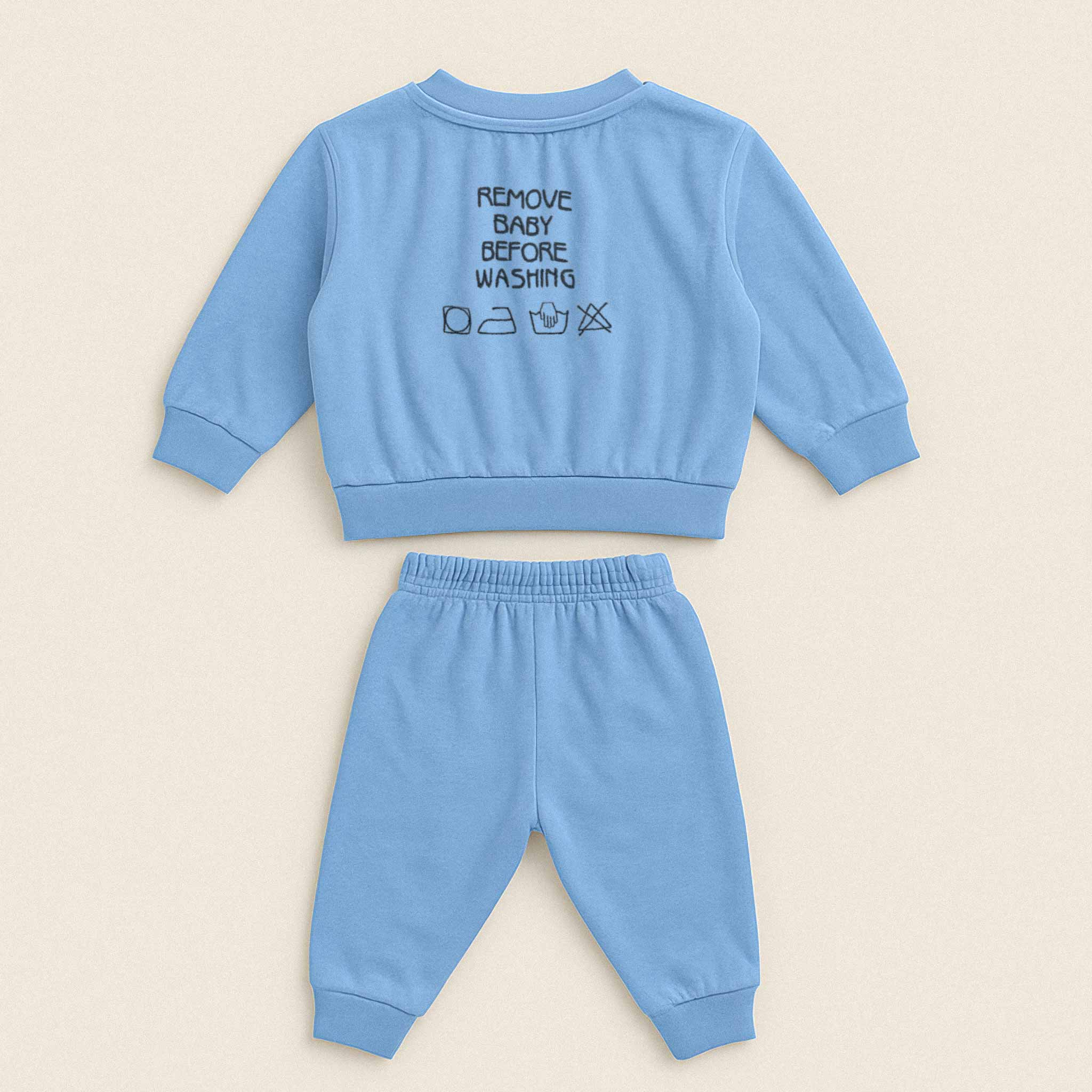 Mavi renkli, sweatshirt ve pantolondan oluşan pamuklu bebek eşofman takımı. Sweatshirt'ün arka tarafında "REMOVE BABY BEFORE WASHING" yazısı ve yıkama sembolleri işlenmiştir.