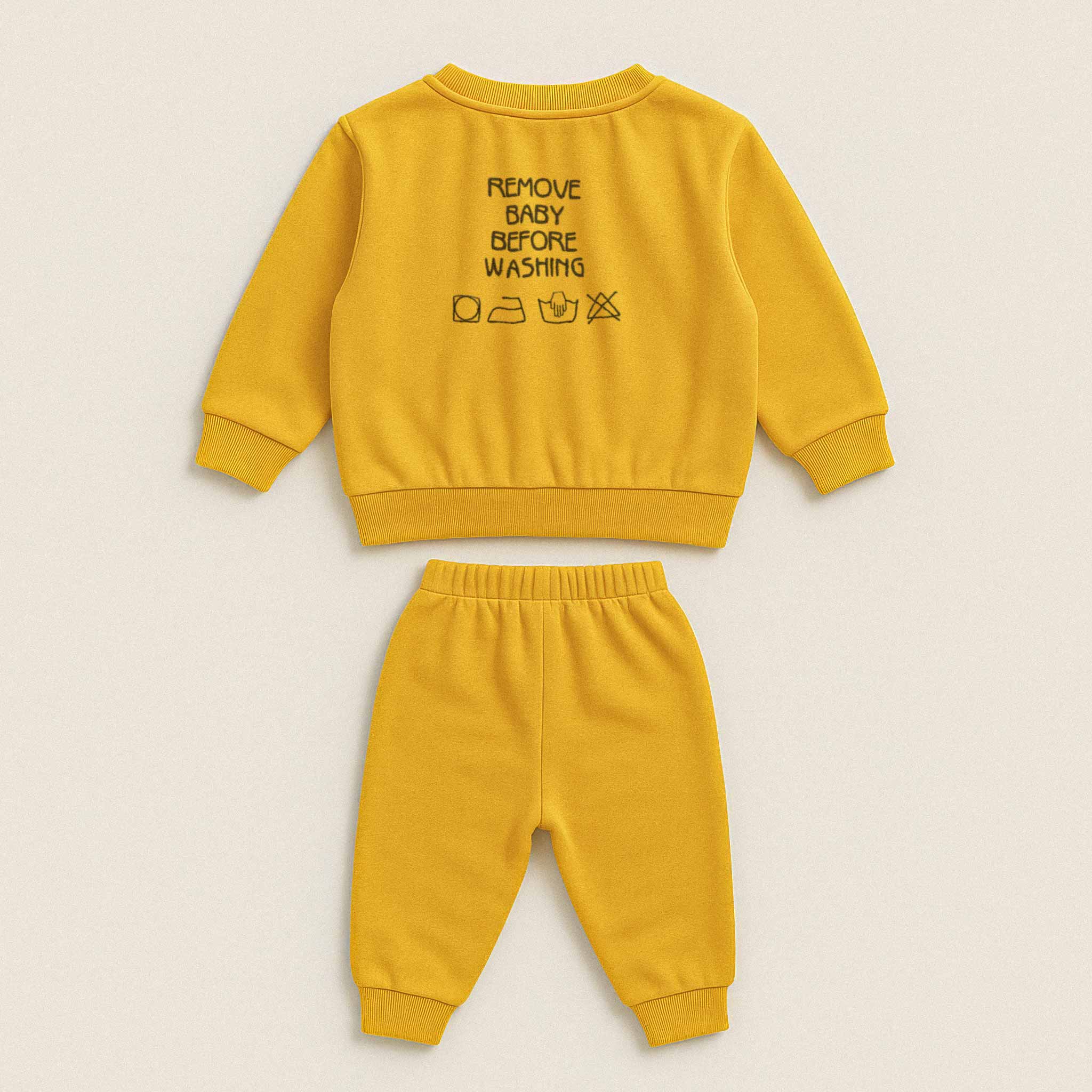 Hardal sarısı renkli, sweatshirt ve pantolondan oluşan pamuklu bebek eşofman takımı. Sweatshirt'ün arka tarafında "REMOVE BABY BEFORE WASHING" yazısı ve yıkama sembolleri işlenmiştir.