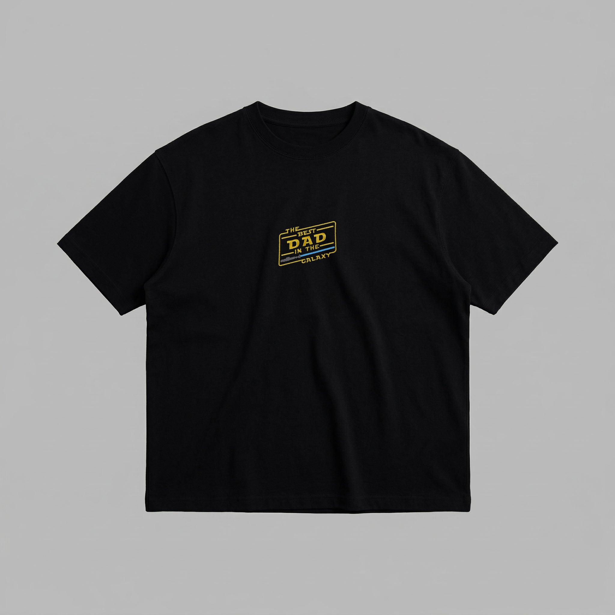 Siyah renkli %100 pamuklu Oeko-Tex sertifikalı loose fit baba tişörtü. Göğüs kısmında sarı renkli, ikonik bilim kurgu açılı çerçeve tasarımıyla "THE BEST DAD IN THE GALAXY" yazısı ve mavi ışın kılıcı detayı nakışlanmıştır. Yüksek kalite Alman nakış işçiliği ile üretilmiştir. Heavyweight kumaşı tok bir duruş sağlarken, nefes alan yapısıyla terletmez. Babalar için tasarlanmış dayanıklı ve rahat premium günlük giyim parçası.