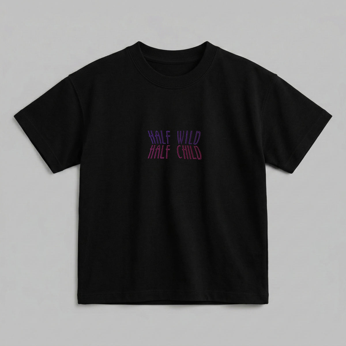 Siyah renkli, %100 pamuklu Oeko-Tex sertifikalı oversize çocuk t-shirt modeli. Göğüs kısmında mor ve pembe iplik geçişleriyle işlenmiş "HALF WILD HALF CHILD" yazılı eğlenceli nakış detayı bulunur. Birinci sınıf Alman nakış ipliği kullanılarak yüksek kalite standartlarında işlenmiştir. Tok duran heavyweight kumaşı, nefes alan ve terletmeyen dokusuyla her mevsim rahatlık sağlayan, havalı ve premium çocuk t-shirt tasarımı.
